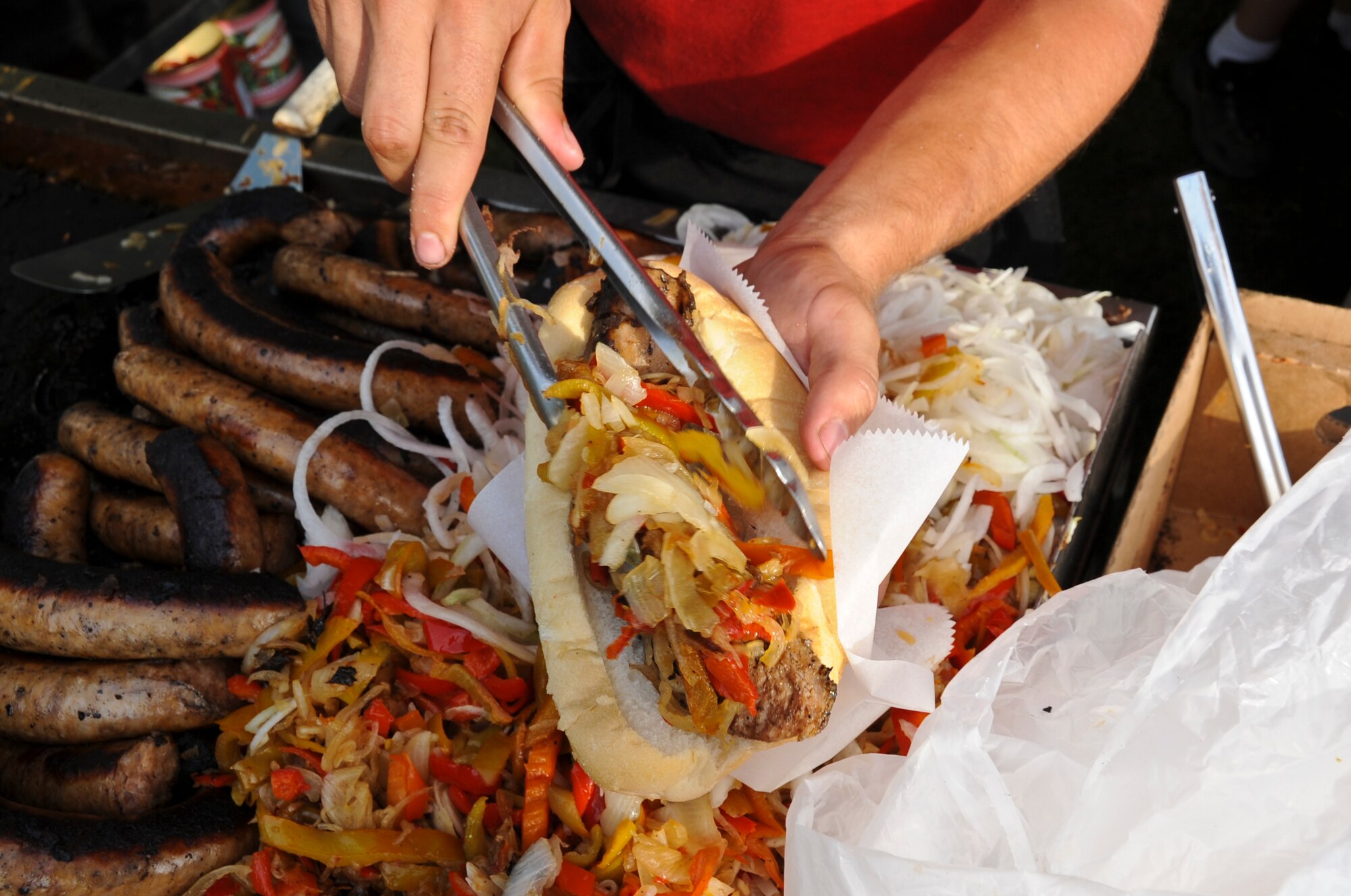 JOINT BASE MCGUIRE-DIX-LAKEHURST, N.J. -- A food vendor loads up onions and peppers onto a bratwurst during the Fourth of July celebration at Doughboy Field on Dix. Eight food and beverage vendors sold items such as funnel cakes, hamburgers, hot dogs, cheese steaks, sausage and peppers, kettle corn and roasted corn on the cob. (U.S. Air Force photo by Senior Airman David Carbajal/Released)