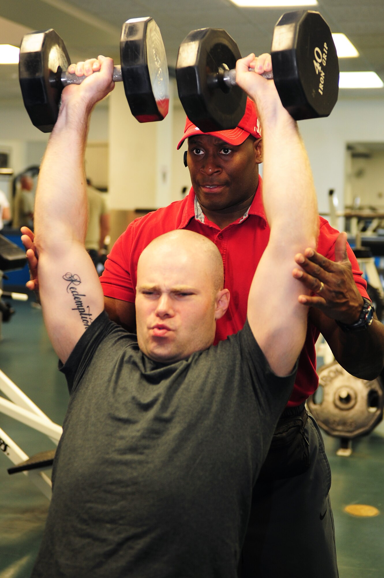 SCOTT AIR FORCE BASE, Ill. -- Staff Sgt. David Johnson, James Gym operations manager, finishes a lifting set while Omar Acosta, a personal trainer working at the James Gym, spots him. Mr. Acosta has been a personal trainer, power lifter and body builder for more than 30 years and is available to help military members improve their fitness. (U.S. Air Force photo/ Staff Sgt. Teresa M. Jennings)