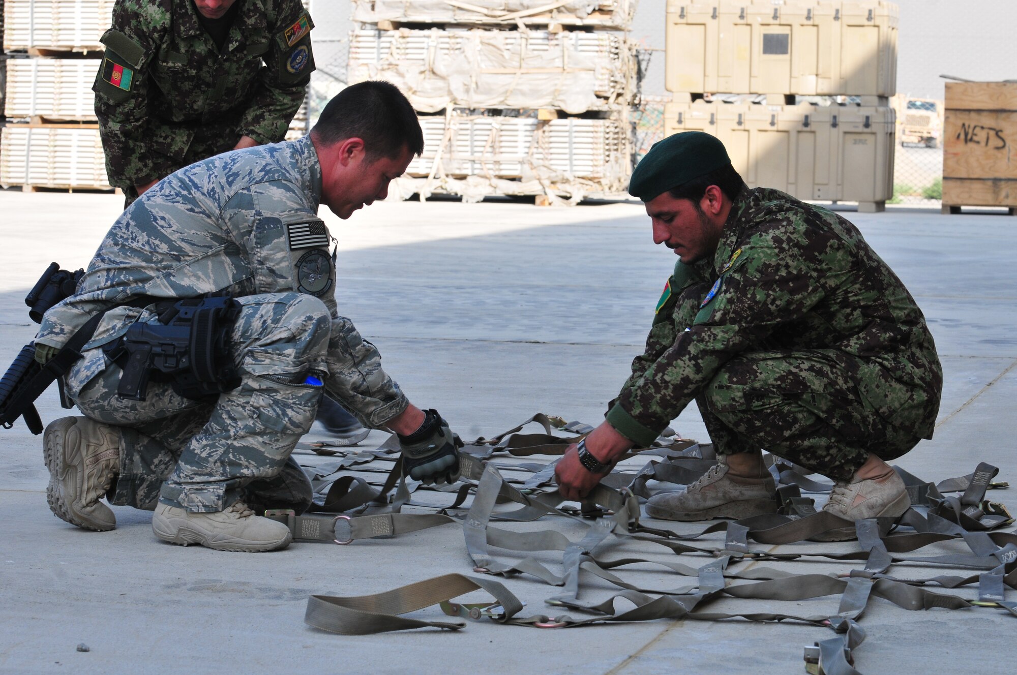 Master Sgt. Chad Weaver, an aerial port adviser assigned to the 439th Air Expeditionary Advisory Squadron, advises an airman from the Afghan air force on how to fasten a cargo strap at the Kabul International Airport, Kabul, Afghanistan, July 6, 2011. The deployed Airman is responsible for helping set the conditions for a professional, fully independent and operationally-capable Afghan Air Force.  Sergeant Weaver is deployed from Kadena AB in Japan.  (U.S. Air Force photo by Tech. Sgt. Brian E. Christiansen)