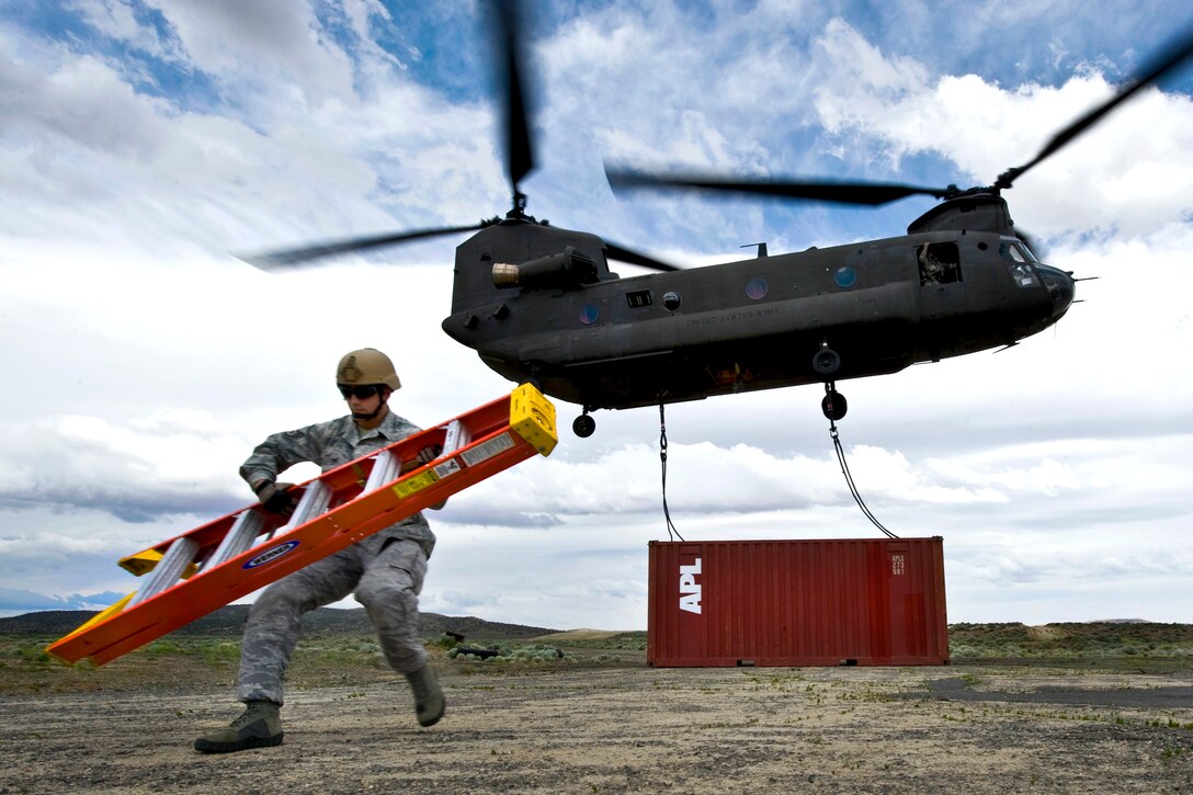 U.S. Air Force Staff Sgt. Jeremy Lowe carries a ladder away from a storage container being transported by a CH-47 Chinook helicopter during a sling-load training exercise at the Senator Harry Reid Readiness and Training Center in Stead, Nev., June 28, 2011. Lowe is an airborne vehicle equipment operator craftsman assigned to the 820th Red Horse Squadron, and the CH-47 crew is assigned to the 1st Battalion, 189th Aviation Company, Nevada Army National Guard.