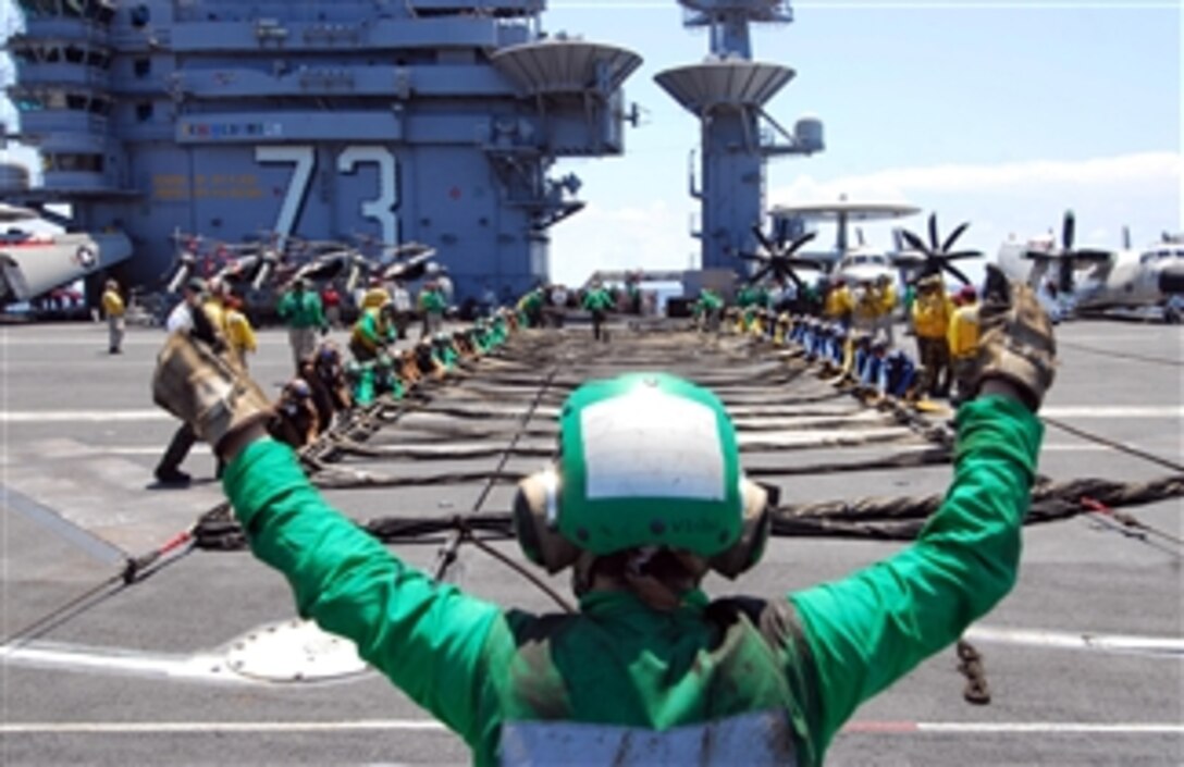 U.S. Navy Petty Officer 3rd Class Ashley Pryor signals for sailors to set up the aircraft barricade during a barricade drill aboard the aircraft carrier USS George Washington (CVN 73) while afloat in the Pacific Ocean on July 2, 2011.  The George Washington is underway in the U.S. 7th Fleet area of responsibility.  