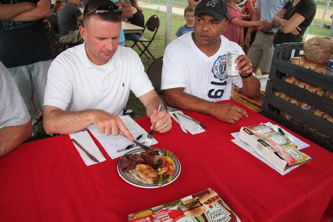 Maj. Brendan C. Burks, Marine Wing Support Squadron 274’s executive officer and judge for the squadron’s Top Chef competition during family day, digs into his plate of bacon-wrapped pork and asparagus July 8.