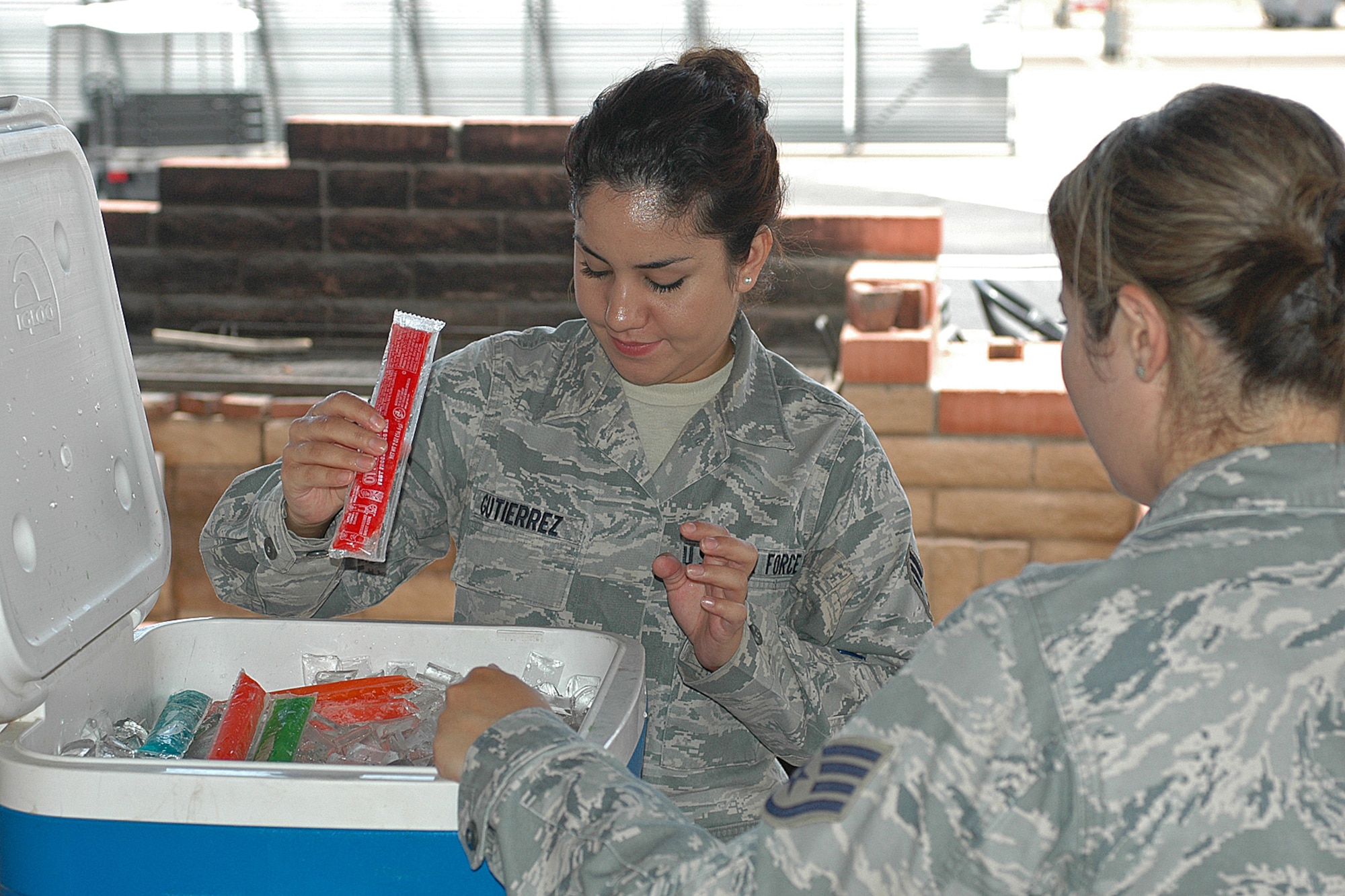 Senior Airman Iana Gutierrez accepts a frozen popsicle from Staff Sgt. Charmaine Pozo, secretary, Junior Enlisted Council, July 8. The frozen treats boosted moral for wing members working in the 100 degree Tucson heat. (U.S. Air Force photo/Staff Sgt. Jordan Jones)
