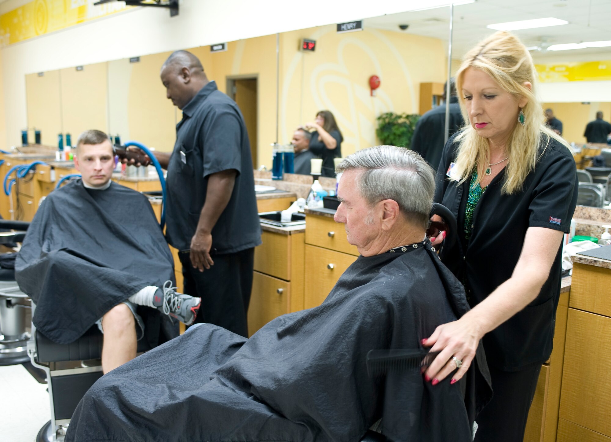 Henry Moseley and Debbie Savu give haircuts at the main barbershop in the Base Exchange on Barksdale Air Force Base, La., July 7. The barbershop gives several hundred haircuts each week to service members and their families. (U.S. Air Force photo by Senior Airman Chad Warren)(RELEASED)