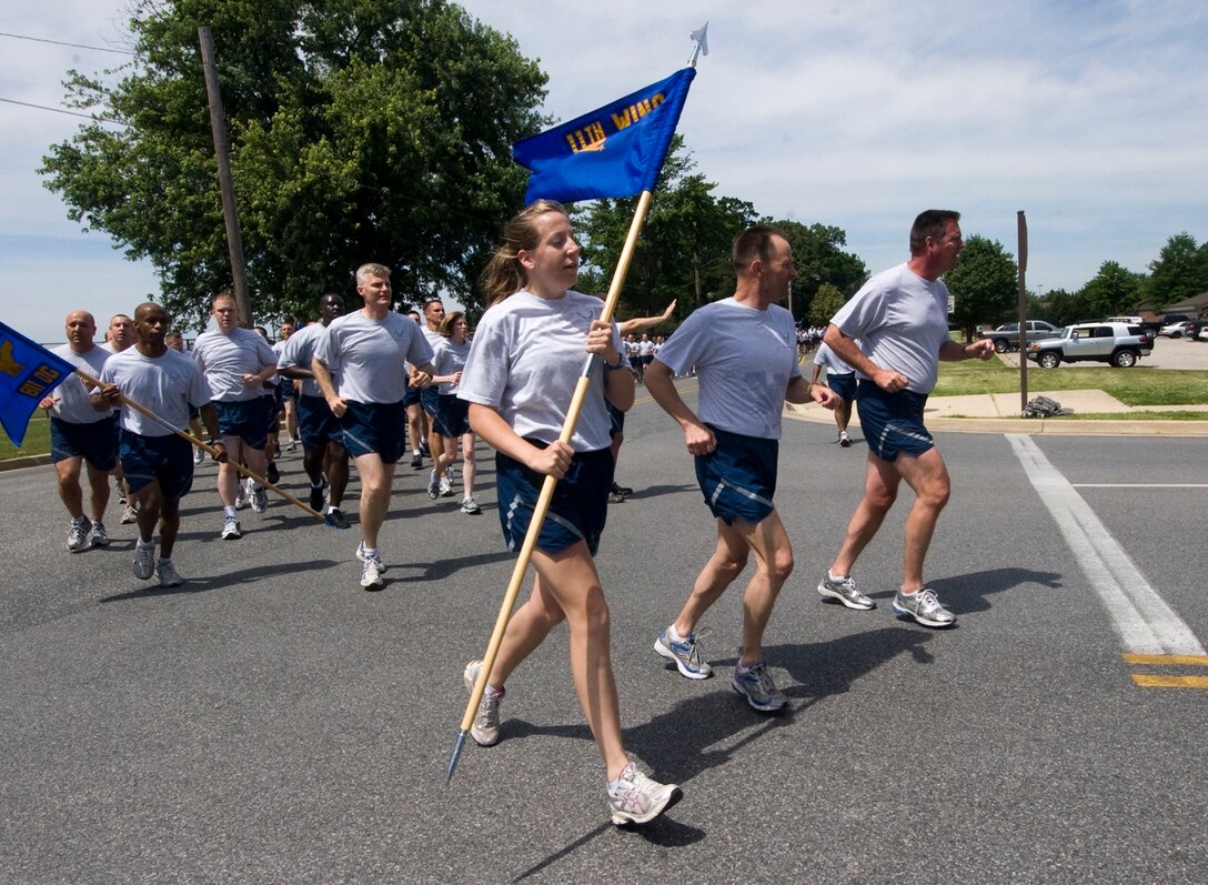 Airman 1st Class Lindsey Beadle, 11th Wing Public Affairs apprentice, carries the 11th Wing guidon next to wing leadership, Col. Ken Rizer, center, 11th Wing/Joint Base Andrews commander and Col. Lee dePalo,  11th Wing/Joint Base Andrews vice commander, during a scheduled wing run here June 2. (Photo by Bobby Jones)