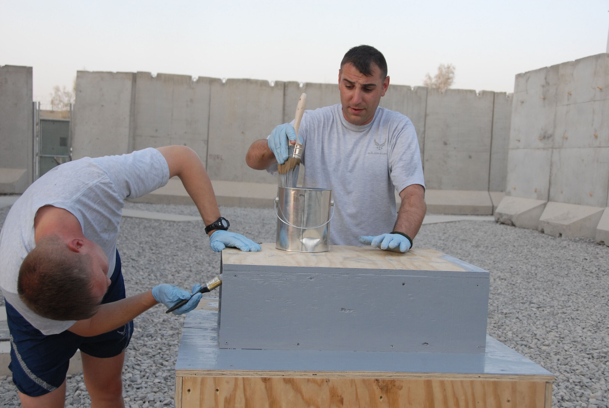 Tech. Sgt. Brian Rice recoats his brush as he helps to paint a uniform collection box July  7, 2011 at Kandahar Airfield, Afghanistan with Lt. Col. Todd Groomes. The plywood box was painted to resemble a safe, which will be locked to prevent Air Force uniforms from being taken by the enemy. Both Lt. Col. Groomes and Tech. Sgt. Rice are members of the 451st Air Expeditionary Wing safety office. (U.S. Air Force photo by Tech. Sgt. Emily F. Alley)