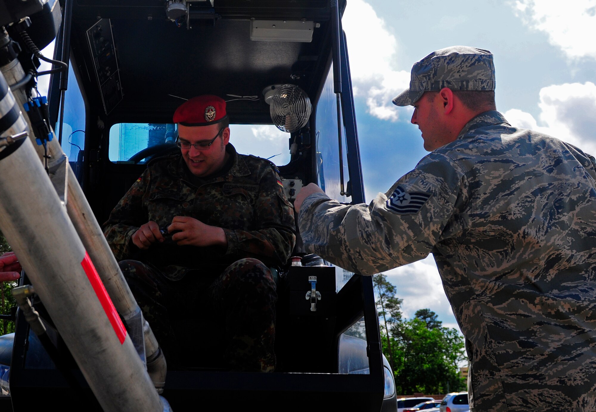 U.S. Air Force Tech. Sgt. Joseph Howell, 86th Vehicle Readiness Squadron mechanic, assists German Armed Forces School of Logistics student, Capt. Sebastian Rechenberger, as he settles in an aircraft de-icer, Ramstein Air Base, Germany, July 6, 2011. The German military members toured Ramstein to help them improve their skills to deliver additional logistics knowledge to their peers. (U.S. Air Force Photo by Airman 1st Class Brea Miller)  