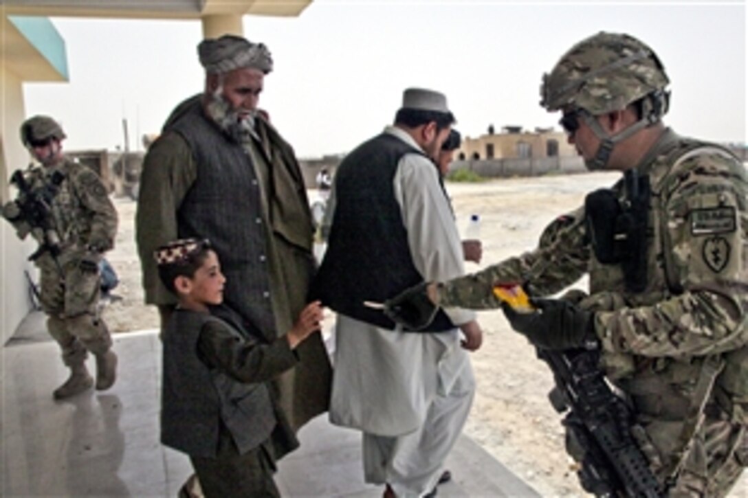 A U.S. Army soldier gives an Afghan boy a piece of chewing gum outside the new Daman District Center in Afghanistan's Kandahar province, July 3, 2011.