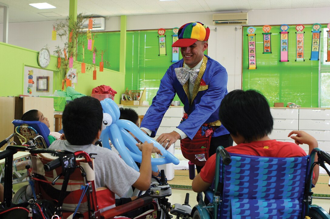 Sgt. Chase V. Morrison, a meteorological and oceanographic forecaster with Headquarters and Headquarters Squadron, Marine Corps Air Station Futenma, presents a child from the Okinawa Children Development Center with a balloon July 9.
