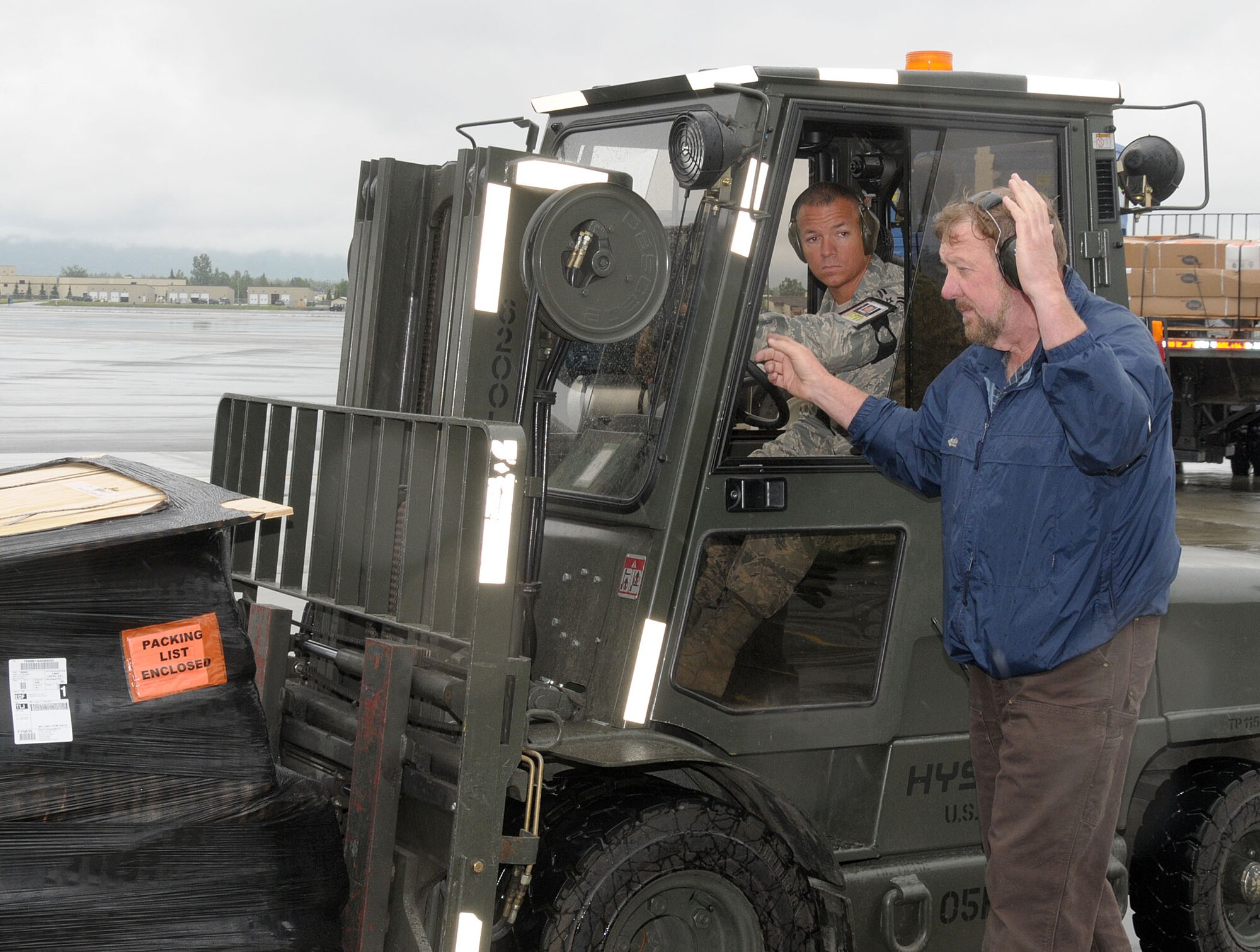Mr. Charles Carr, Weight Supervisor 7 in Air Terminal Operations, Elmendorf Air Force Base, Anchorage, Alaska guides Airman First Class Jesse Kramer, Air Terminal Operations, Logistics Readiness Squadron, 146th Airlift Wing, Channel Islands Air National Guard Station, Calif. as he loads an aircraft delivering supplies to the interior of Alaska at Joint Base Elmendorf-Richardson on June 15, 2011. The 146th AW sent three squadrons to JBER from June 4 to June 18, 2011. The Air Terminal Operations Squadron, Logistics Readiness Squadron, and Security Forces Squadron moved down range to complete their respective annual training requirements. Photo by Tech. Sgt. Alex Koenig