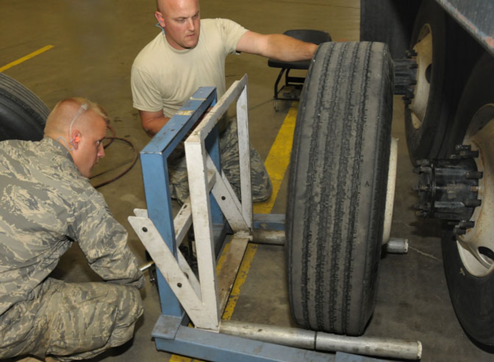 Senior Airman Tobias Burrier (left) and Staff Sergeant Jeffrey Strong (right) from Vehicle Maintenance, Logistics Readiness Squadron, 146th Airlift Wing, Channel Islands Air National Guard Station, Calif. maneuver a tire onto a large dump truck during a deployment to Joint Base Elmendorf Richardson on June 8, 2011. The 146th AW sent three squadrons to JBER from June 4 to June 18, 2011. The Air Terminal Operations Squadron, Logistics Readiness Squadron, and Security Forces Squadron moved down range to complete their respective annual training requirements. Photo by Tech. Sgt. Alex Koenig

