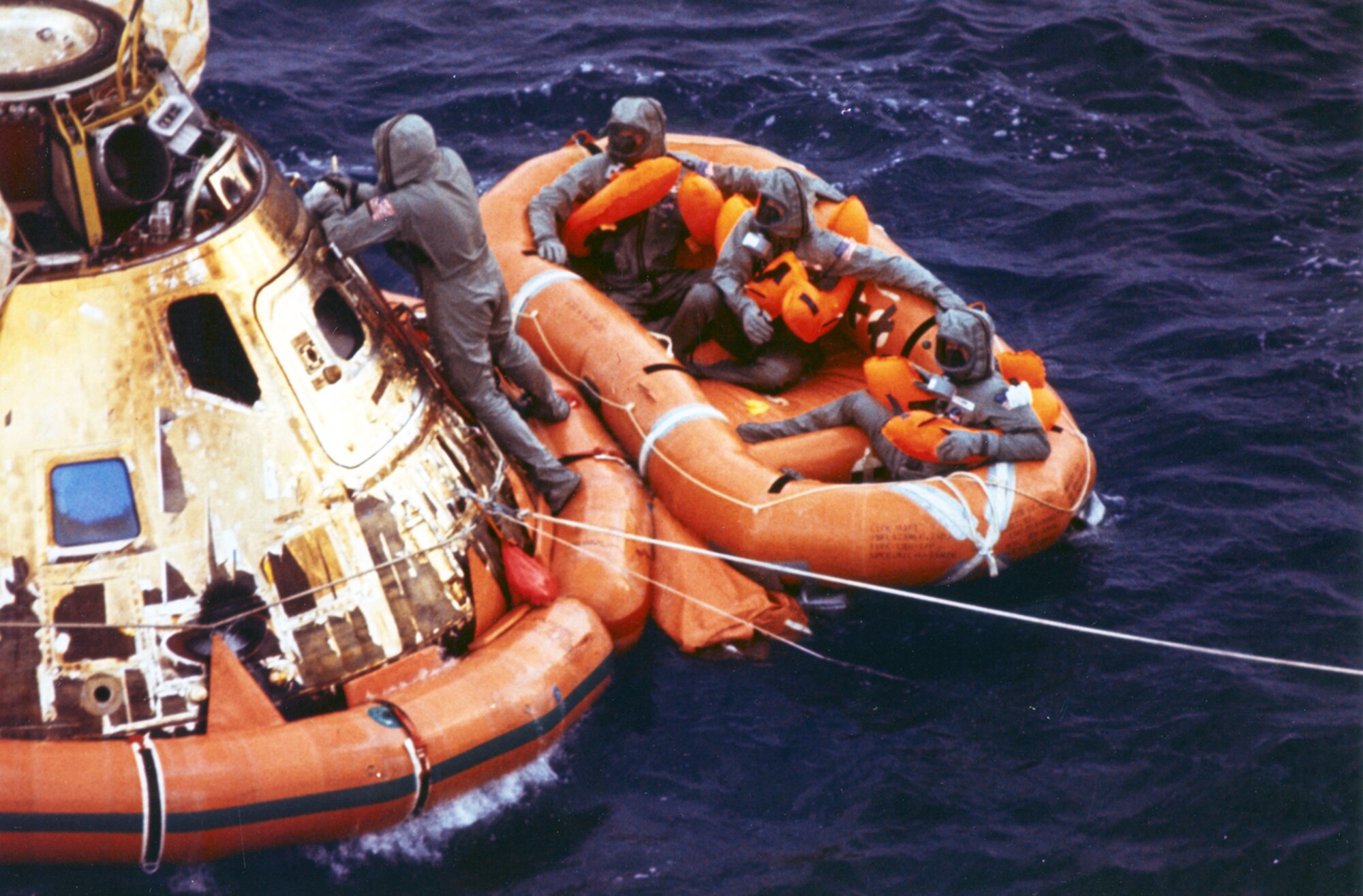 Pararescueman Lt. Clancy Hatleberg closes the Apollo 11 spacecraft hatch as astronauts Neil Armstrong, Michael Collins and Buzz Aldrin, Jr await helicopter pickup from their life raft. They splashed down at 12:50 pm EDT July 24, 1969, 900 miles southwest of Hawaii after asuccessful lunar landing mission. (photo/NASA)