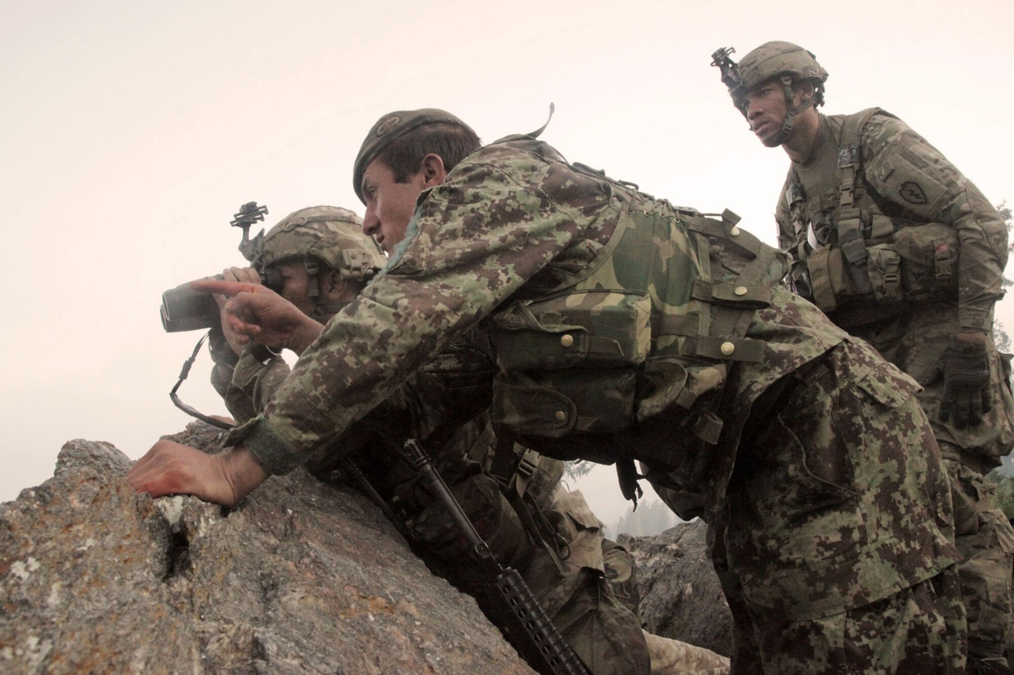 BAGRAM AIRFIELD, Afghanistan -- U.S. Army soldiers from D Company, 2nd Battalion, 35th Infantry Regiment, alongside an Afghanistan National Army soldier, survey the valley below for insurgent activity during Operation Hammer Down in the Watahpur District of Kunar province, Afghanistan, June 26. The operation was a coalition effort to disrupt insurgents operating and training throughout the Pech Valley. (U.S. Army photo by Spc. Tia Sokimson)