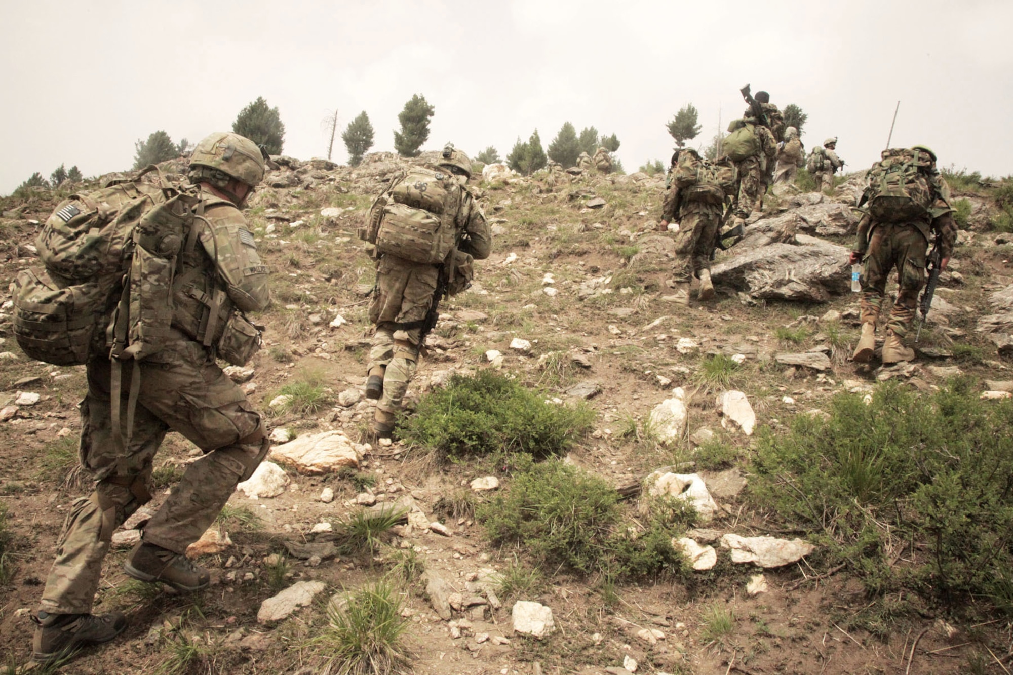 BAGRAM AIRFIELD, Afghanistan -- U.S. Army soldiers from D Company, 2nd Battalion, 35th Infantry Regiment, alongside the Afghanistan National Army soldiers, advance toward a hill top to set up security during Operation Hammer Down in the Watahpur District of Kunar province, Afghanistan, June 26. The operation was a coalition effort to disrupt insurgents operating and training throughout the Pech Valley. (U.S. Army photo by Spc. Tia Sokimson)