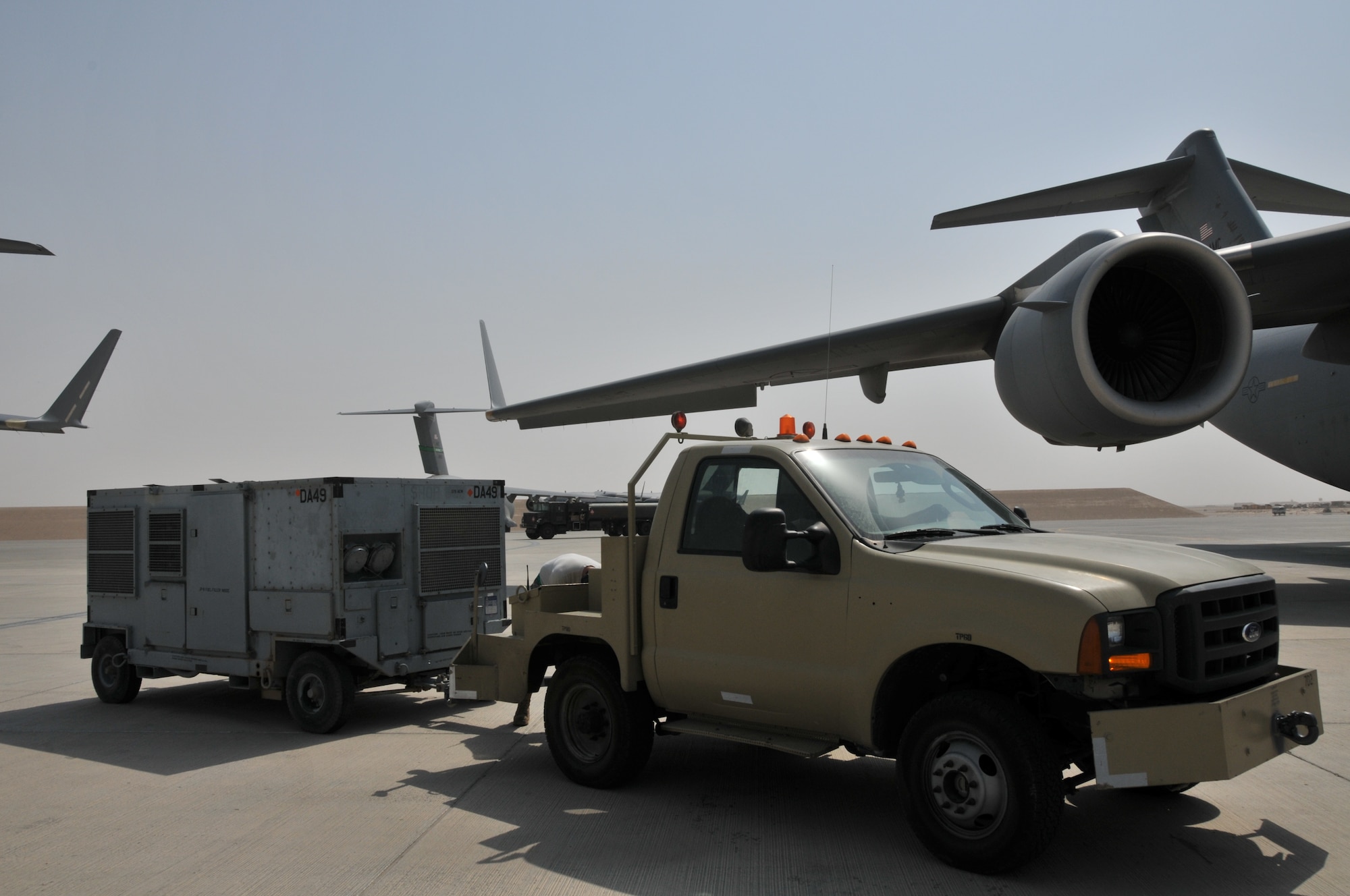 Airmen from the 379th Expeditionary Maintenance Squadron Aerospace Ground Equipment flight transport a piece of equipment away from a C-17 Globemaster III, July 4, at an undisclosed location in Southwest Asia. (U.S. Air Force photo/ Senior Airman Eric Summers Jr.)