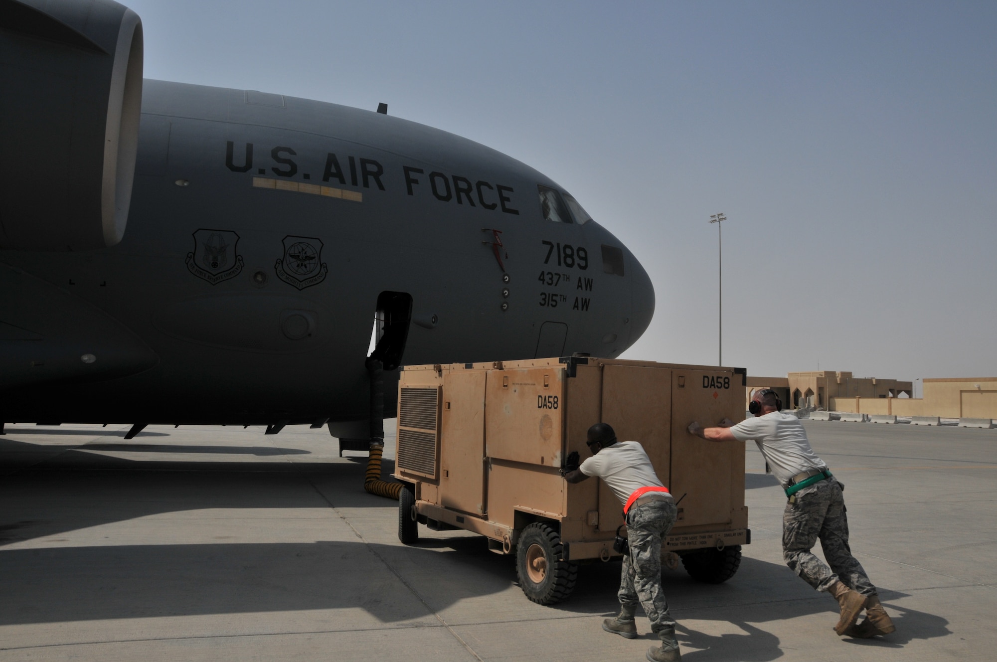 Airmen from the 379th Expeditionary Maintenance Squadron Aerospace Ground Equipment flight push a MA-3D airconditioner unit toward a C-17 Globemaster III so they can connect it to the aircraft, July 4, at an undisclosed location in Southwest Asia. The flight supplies and maintains ground equipment that can duplicate aircraft systems while it is grounded. (U.S. Air Force photo/ Senior Airman Eric Summers Jr.)