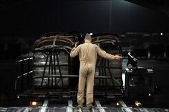 Staff Sgt. Russell Johnson, 816th Expeditionary Airlift Squadron loadmaster, marshals a K-loader with bundles of Meals, Ready to Eat in place behind a C-17 Globemaster III July 8, 2011. Later, the C-17 crew airdropped a total of 48,000 pounds of MREs to resupply forces on the ground in Afghanistan. It was one of two re-supply airdrop missions flown by the crew that day. (U.S. Air Force photo/Master Sgt. Jeffrey Allen)