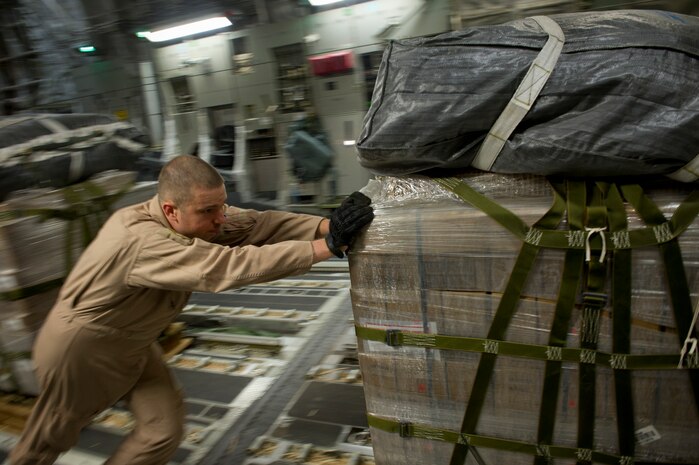 Staff Sgt. Russ Johnson, 816th Expeditionary Airlift Squadron loadmaster, pushes one of 40 pallets of Meals, Ready to Eat onto a C-17 Globemaster III at Bagram Airfield, Afghanistan, July 8, 2011. Throughout the crew's 15-hour mission, they airdropped more than 73,200 pounds of JP8 fuel and 48,000 pounds of MREs. (U.S. Air Force photo by Staff Sgt. David Salanitri)