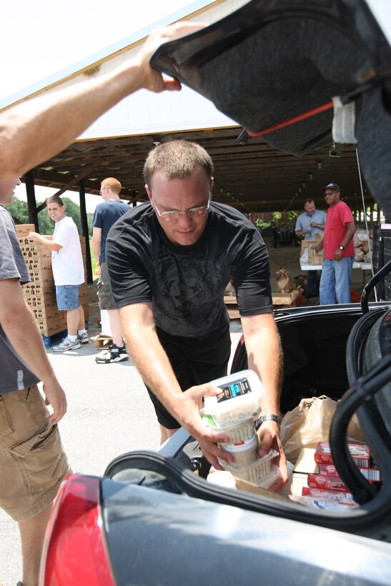 Petty Officer 2nd Class Darren McPhee, a corpsman with Charlie Surgical Company, 2nd Medical Battalion, 2nd Marine Division puts food into the trunk of car during the drive-thru Food Bank event at the American Legion, hosted by Onslow Community Outreach’s soup kitchen, July 11. The drive-thru is open to all Jacksonville residents and registration for the event can be done at the American Legion on the day the event. (Official U.S. Marine Corps photo by Pfc. Nik S. Phongsisattanak)