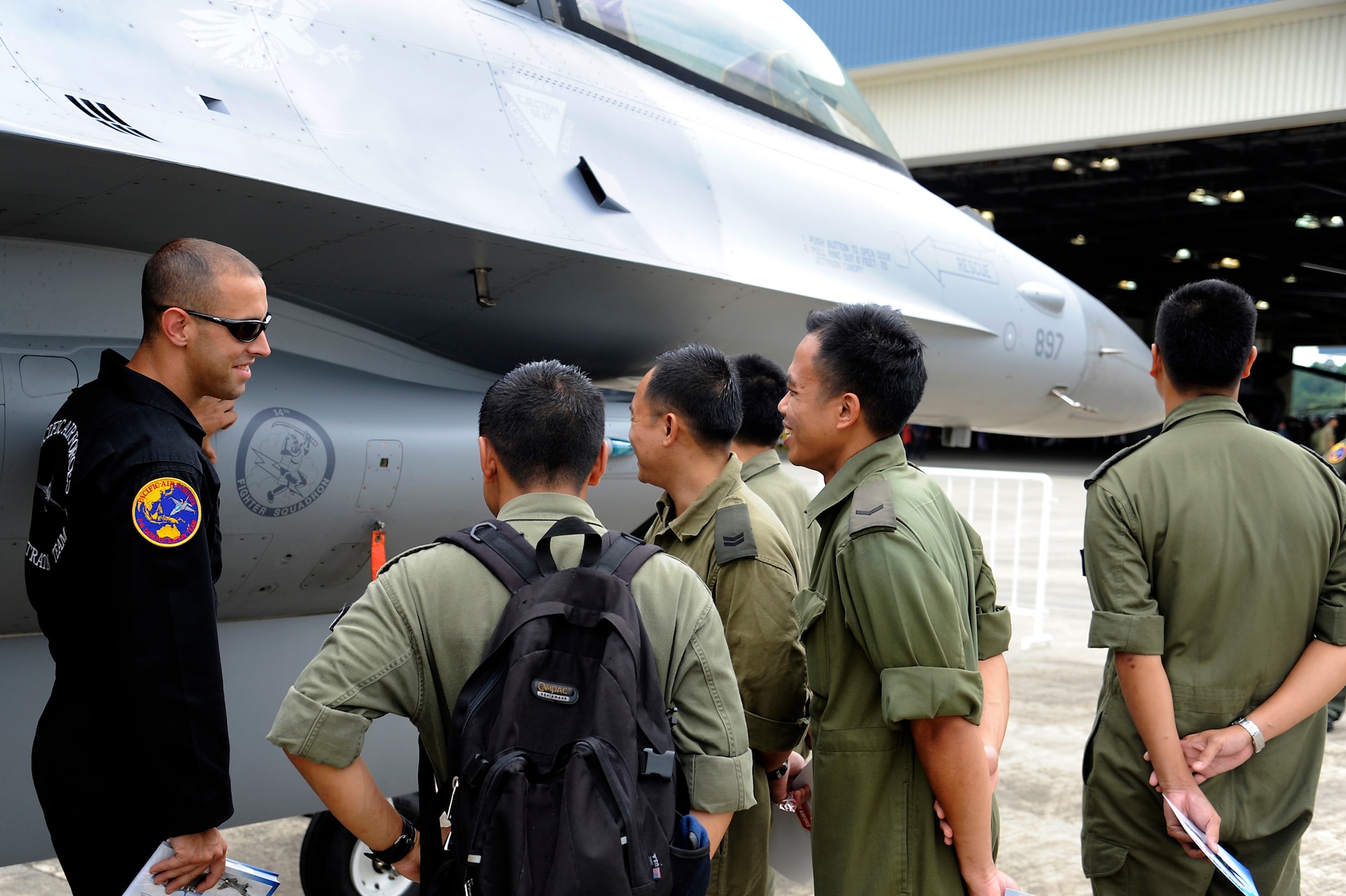 Brunei Darussalam -- Staff Sgt. Nathan Bolander, Pacific Air Forces Demonstration Team member, shows foreign military members the 14th Airlift Squadron patch on the side of a F-16 Fighting Falcon during the 3rd Biennial Brunei Darrussalam International Defense Exhibition July 6. Misawa personnel showcased two F-16 Fighting Falcons through static displays and aerial demonstrations for the first time during BRIDEX. (U.S. Air Force photo/Staff Sgt. Marie Brown/Released)