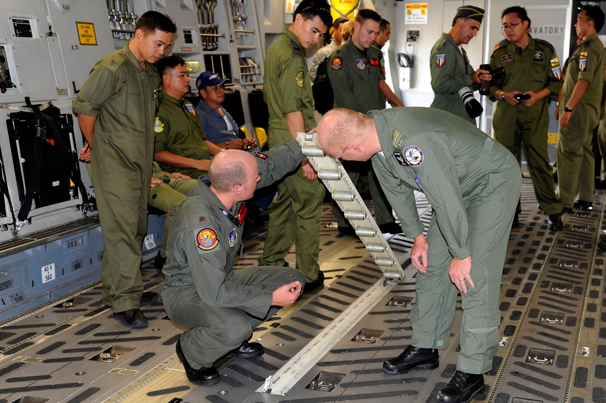 Brunei Darussalam -- Maj. Mike Pasquino, kneeling left, 15th Wing C-17 pilot, shows a British pilot the design of the C-17 Globemaster III at the static display during the 3rd Biennial Brunei Darussalam International Defense Exhibition in Brunei Darussalam July 6. Pacific Air Forces showcased a C-17 Globemaster III and two F-16 Fighting Falcons through static displays and aerial demonstrations for the first time during BRIDEX. (U.S. Air Force photo/Staff Sgt. Marie Brown/Released)