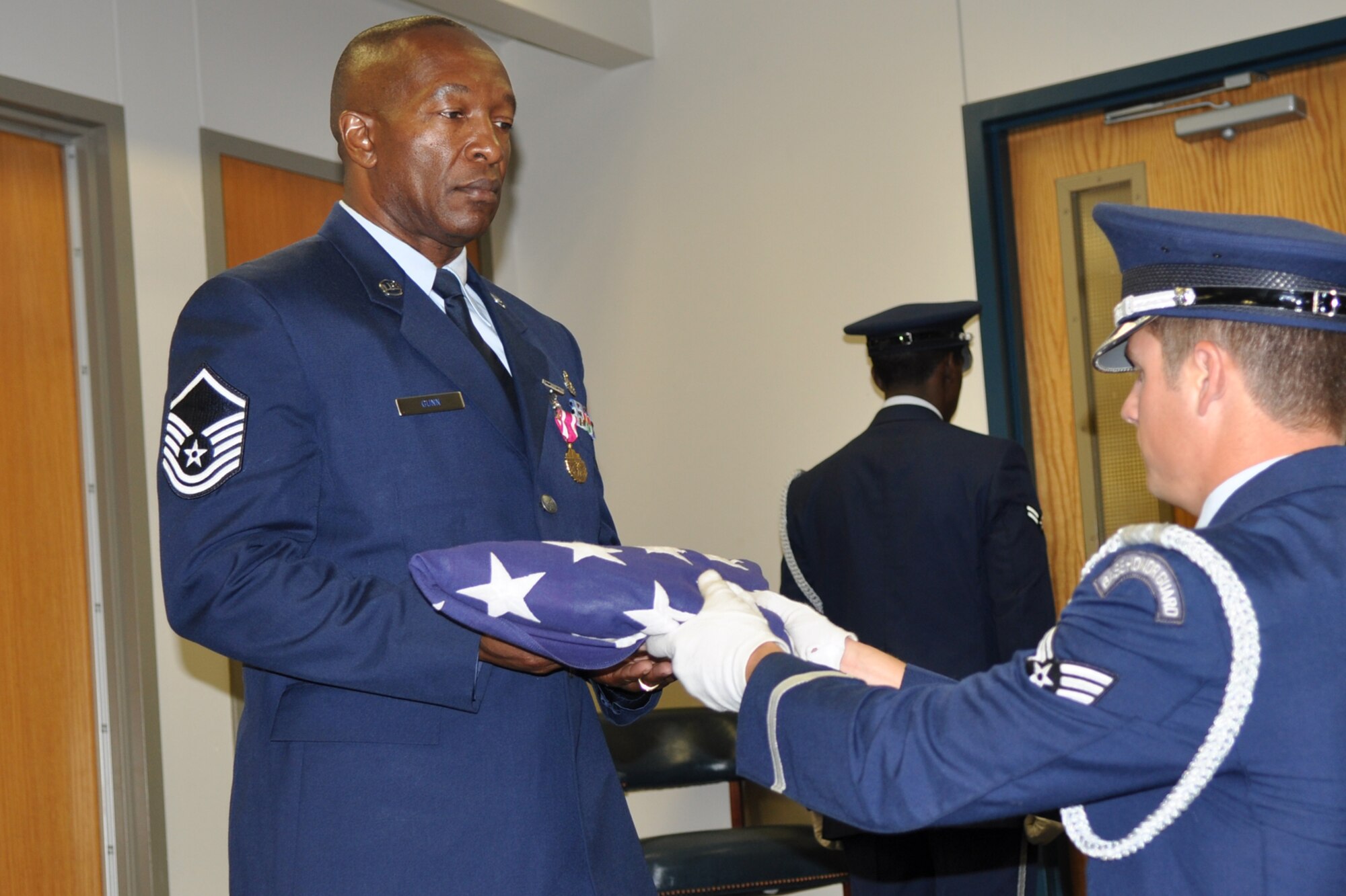 Master Sgt. Jonathan Gunn, electronics and environmental specialist with the 307th Bomb Wing, accepts a U.S. flag from a member of the Honor Guard during his retirement ceremony at the 307th Bomb Wing Headquarters building on Barksdale Air Force Base, La., July 9. In addition to the flag presentation, Gunn received a shadow box containing military medals he earned during his 33 years in the Air Force. (U.S. Air Force photo/Staff Sgt. Ted Daigle)