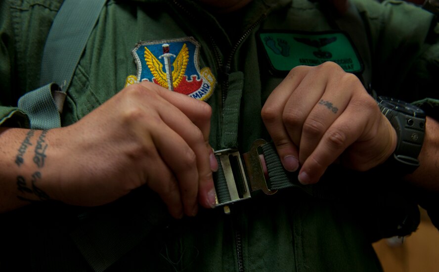 U.S. Air Force Staff Sgt. Antonio Delvercchio, 41st Rescue Squadron flight engineer, buckles an LPU-10/P while demonstrating the proper equipment needed before taking off on a flight at Moody Air Force Base, Ga., July 11, 2011. The LPU-10/P works by pulling downward and slightly outward on the lanyards that extend from the lower front corner of each container and if failure occurs, the life preserver may be orally inflated. (U.S. Air Force photo by Airman 1st Class Joshua Green/Released)
