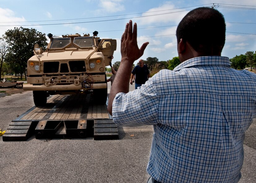 Angus Friend of 96th Logistics Readiness Squadron cargo movement, helps the driver of an Air Force Mine Resistant Ambush Protected vehicle find the center of the trailer before the vehicle is shipped out.  The 45 people in LRS' cargo movement unload and ship out an almost 15,000 pieces through commercial carriers each year.  Their in-house capabilities allow them to create virtually any type of shipping material needed to store, secure and ship an item from Eglin.  (U.S. Air Force photo/Samuel King Jr.)   
