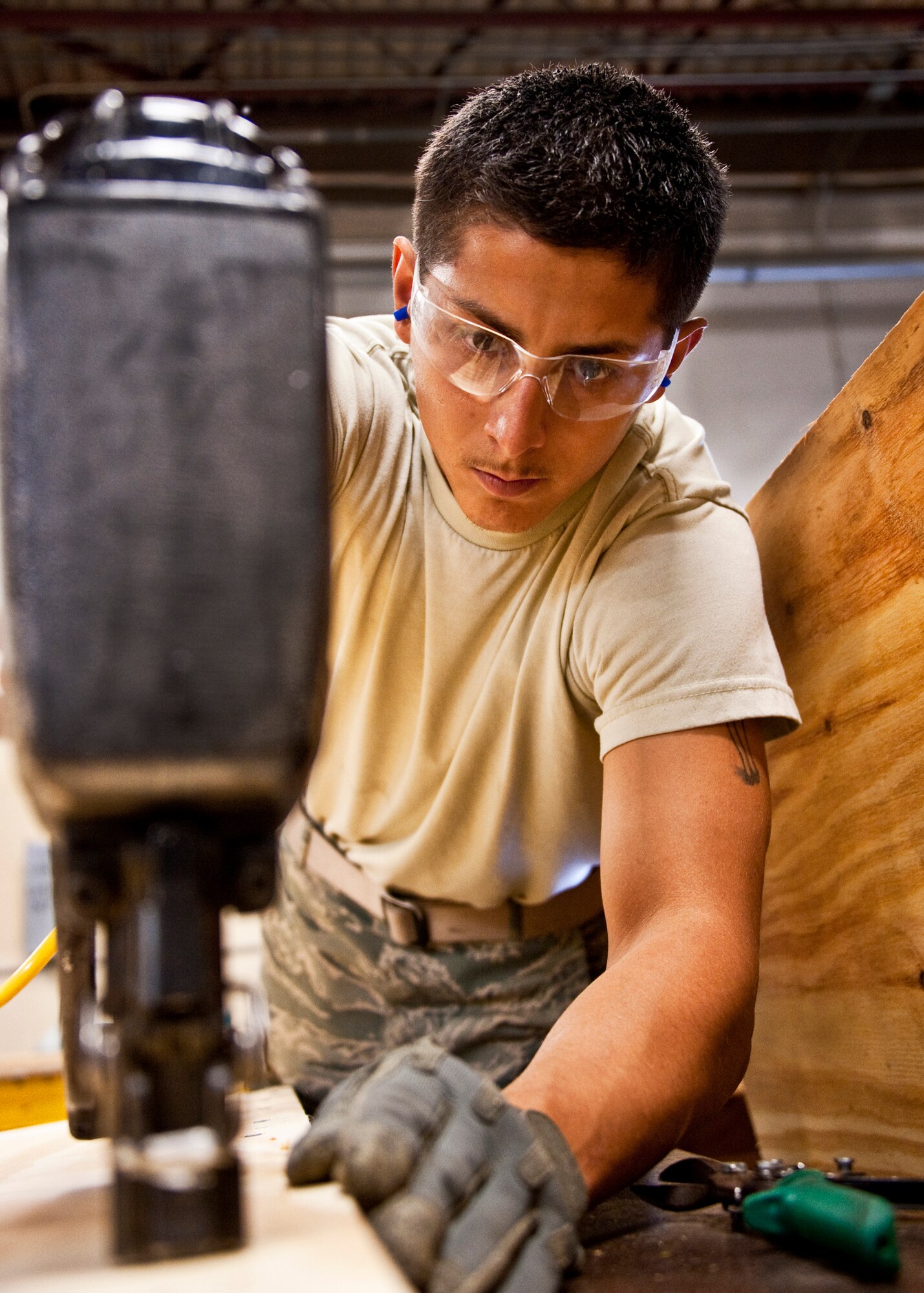 Airman 1st Class Jeremy Gonzales of 96th Logistics Readiness Squadron cargo movement, nails the board into place with a nail gun.  The wood will be used to create a box to secure and ship a large item from the base.  Measurements of the items to be shipped are taken and used to produce specifications for the type of box needed to ship it.  Personnel in the wood shop can build a box to meet those specifications needed to secure and ship the item.  (U.S. Air Force photo/Samuel King Jr.)   