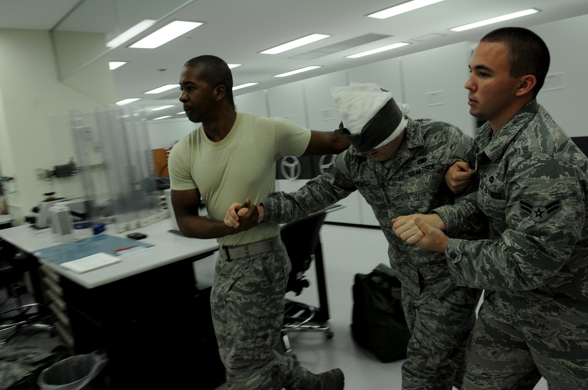 Airmen 1st Class Alexander Tatum and Richard Bower, both from the 18th Component Maintenance Squadron, carry a simulated victim, who had hazardous material spilled in his eyes, to a water station to irrigate his eyes during an exercise July 11 at Kadena Air Base, Japan. Kadena's personnel are participating in exercise Beverly High 11-05 to stay prepared for real-world contingencies.  (U.S. Air Force photo/Airman 1st Class Jarvie Z. Wallace)

