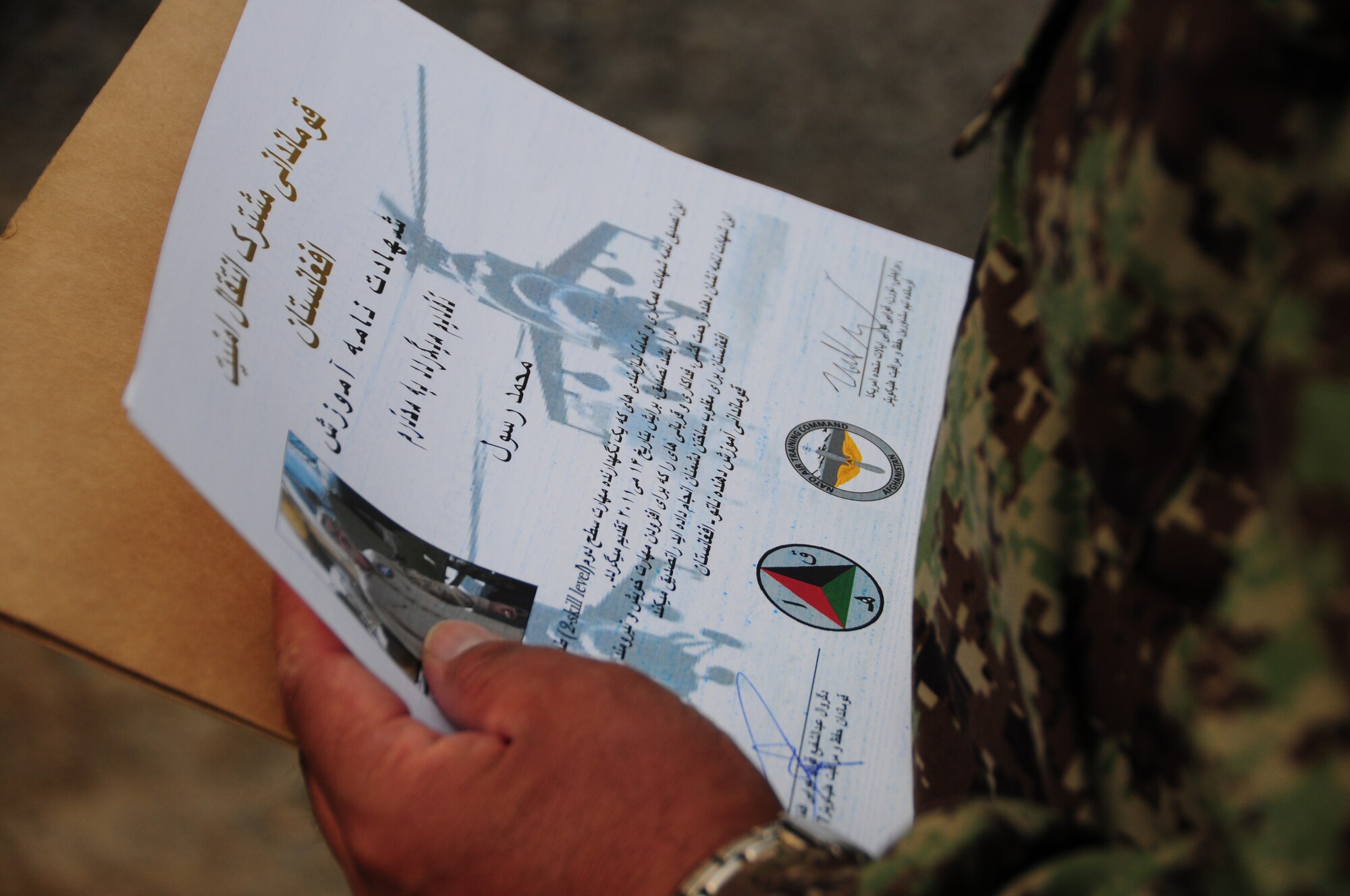 An Afghan Air Force maintenance graduate receives his diploma at the first-ever rotary-wing maintenance train-the-trainer course at Kabul International Airport, Kabul, Afghanistan July 11, 2011.  The graduating group is now qualified to instruct three different training levels outlined in their training records.  Master Sgt. Walt Shaffer, deployed from Kirtland AFB, N.M., facilitated the training.  (U.S. Air Force photo by Senior Airman Amber Williams)