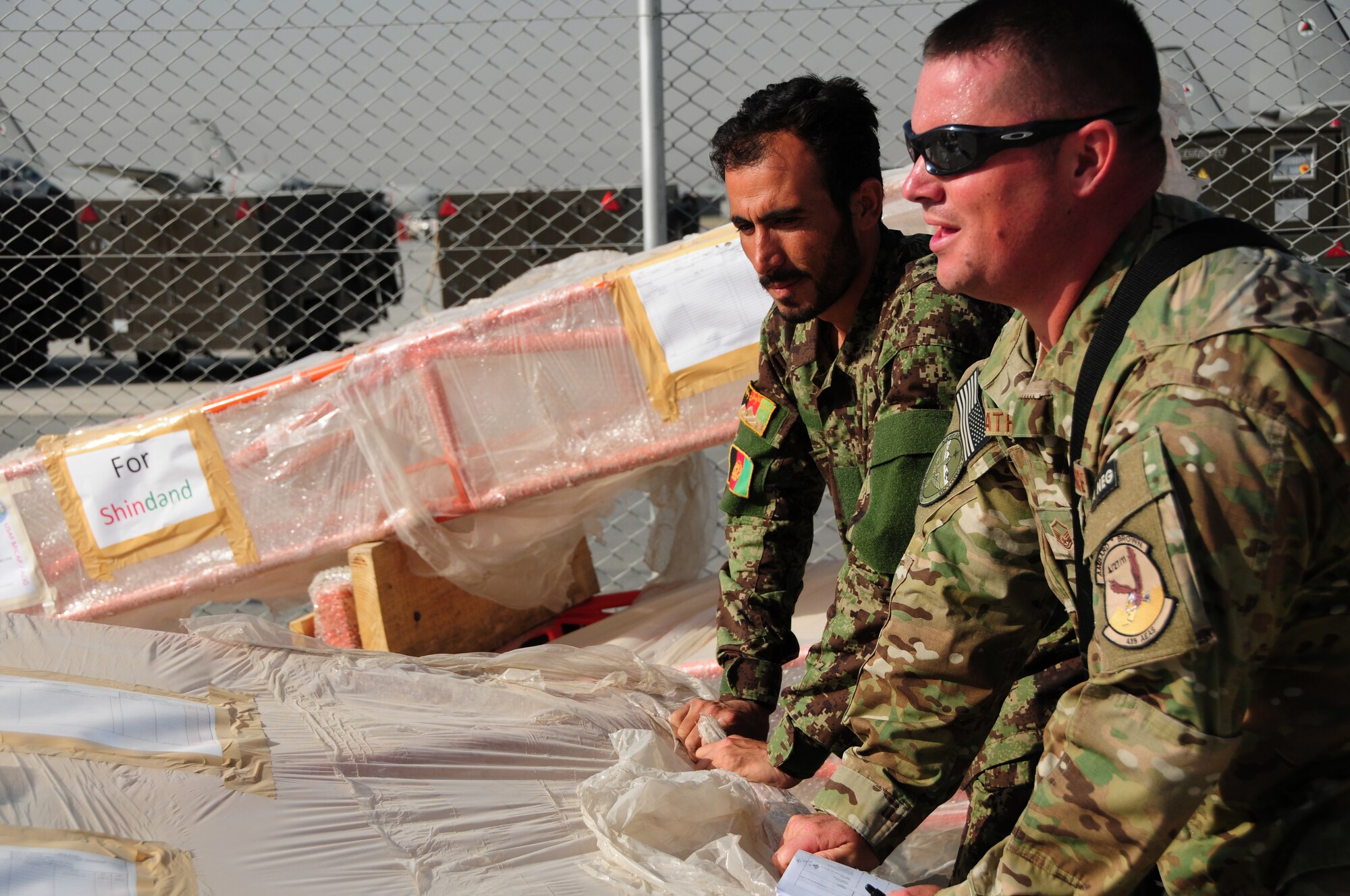 An Afghan Air Force Airman and Master Sgt. Robert Weatherly, 439th Air Expeditionary Advisory Squadron, work together to move cargo for a recent shipment of AAF helicopter parts at Kabul International Airport, Kabul, Afghanistan, June 6, 2011. Deployed Airmen here at the 438th Air Expeditionary Wing, are responsible for setting the conditions for a professional, fully independent and operationally-capable Afghan Air Force.  Sergeant Weatherly is deployed from Andrews Air Force Base. (U.S. Air Force photo by Senior Airman Amber Williams)
