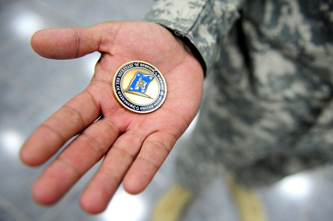 A U.S. Army soldier holds a coin he received from U.S. Defense Secretary Leon E. Panetta at Camp Victory, Iraq, July 11, 2011.