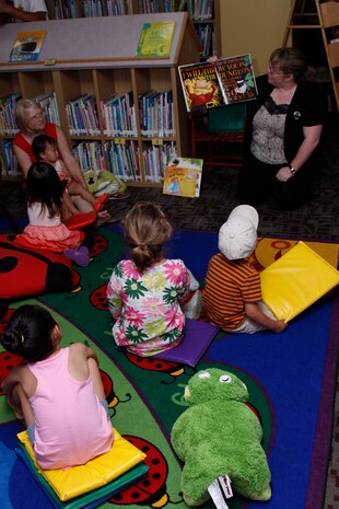 Jessica E. Ossiander, a station library technician, reads a book to children during Monday story time for the Summer Reading Program at the station library here July 11. The Summer Reading Program is focused on helping the children to better themselves in reading by providing fun activities to complete and topics to read.