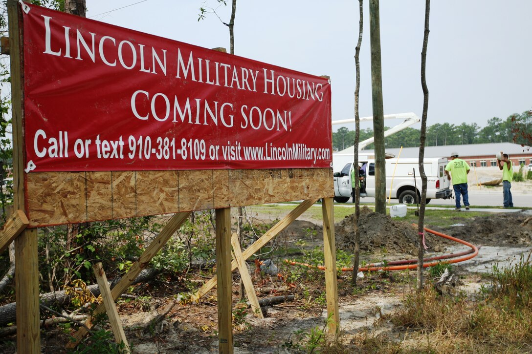 A Lincoln Military Housing coming soon sign stands outside of the new Heroes Village, aboard Marine Corps Base Camp Lejeune, as construction workers set up temporary lighting. Heroes Village is an on-base house neighborhood led by Lincoln Military Housing, a Department of the Navy partner in building 560 homes along Brewster Blvd. aboard the base.