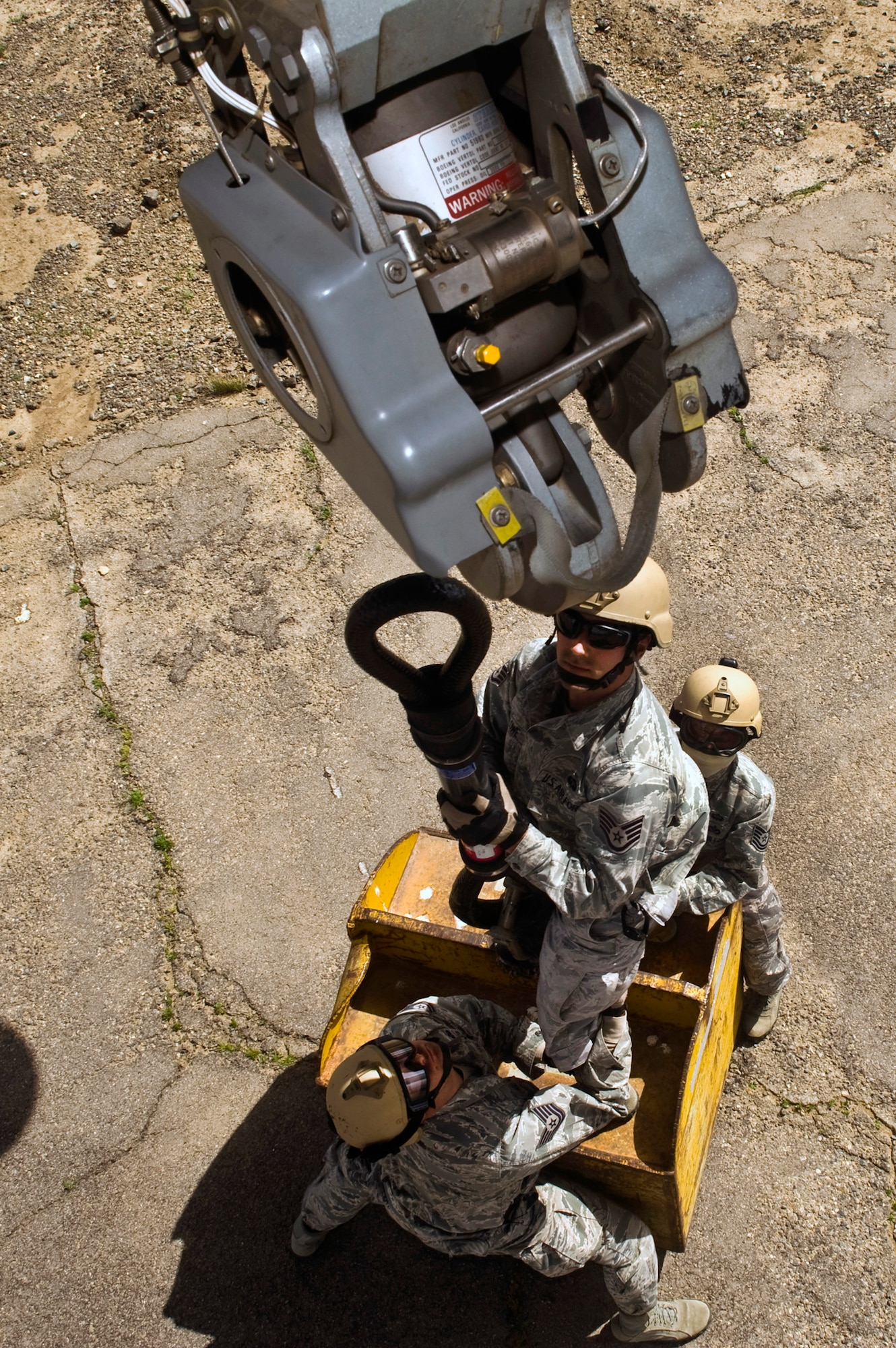 U.S. Air Force Staff Sgt. Jeremy Lowe, center, 820th RED HORSE Squadron airborne flight vehicle equipment maintenance craftsman, rigs an 11,000-pound steel training block to a Nevada Army National Guard CH-47 Chinook helicopter while Tech. Sgt. Joshua Tully, left, 820 RHS fire emergency service craftsman, and Tech. Sgt. Joshua Ramos, right, 820 RHS airborne electrical systems craftsman, provide safety observation June 28, 2011, at the Senator Harry Reid Readiness and Training Center in Stead, Nev. Members of the Nevada Army National Guard 1st Battalion, 189th Aviation Company and the 820 RHS airborne flight trained together to improve their expertise in conducting air drops and sling-load operations. (U.S. Air Force photo by Senior Airman Brett Clashman/Released)
