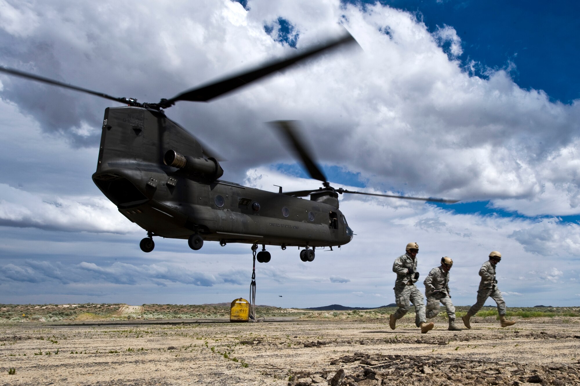 From left to right, U.S. Air Force Capt. Kenneth Cooper, 820th RED HORSE Squadron airborne flight commander, Tech. Sgt. Joshua Tully, 820 RHS fire emergency service craftsman, and Capt. Christopher Smith, 820 RHS airborne flight officer in charge, run for protection from the prop wash of a Nevada Army National Guard CH-47 Chinook helicopter after rigging an 11,000-pound steel training block to the helicopter June 28, 2011, at the Senator Harry Reid Readiness and Training Center in Stead, Nev. Members of the Nevada Army National Guard 1st Battalion, 189th Aviation Company and the 820 RHS airborne flight trained together to improve their expertise in conducting air drops and sling-load operations. (U.S. Air Force photo by Senior Airman Brett Clashman/Released)



