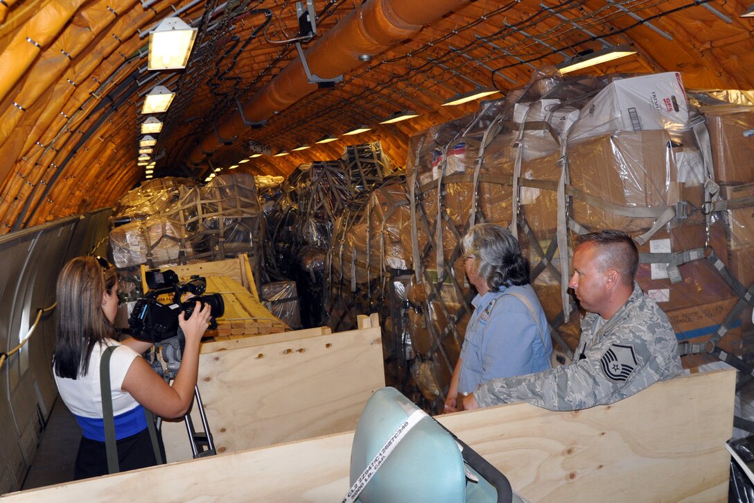 YOUNGSTOWN AIR RESERVE STATION, Ohio -- Air Force Reserve Master Sgt. Kevin Massie (far right), superintendent of the 910th Airlift Wing's 76th Aerial Port Squadron, watches as a reporter from a Youngstown-area media outlet films pallets of humanitarian cargo inside a KC-10 aircraft on the flightline here, July 11, 2011. Sergeant Massie and a team of 76th APS Citizen Airmen prepared 22 Air Force pallets containing 61,000 pounds of supplies from the Mission of Love, based in nearby Austintown, Ohio, for shipment to the communities of Progreso, Yoro and Santa Rita, Yoro, Honduras. U.S. Air Force photo by Master Sgt. Bob Barko Jr. 