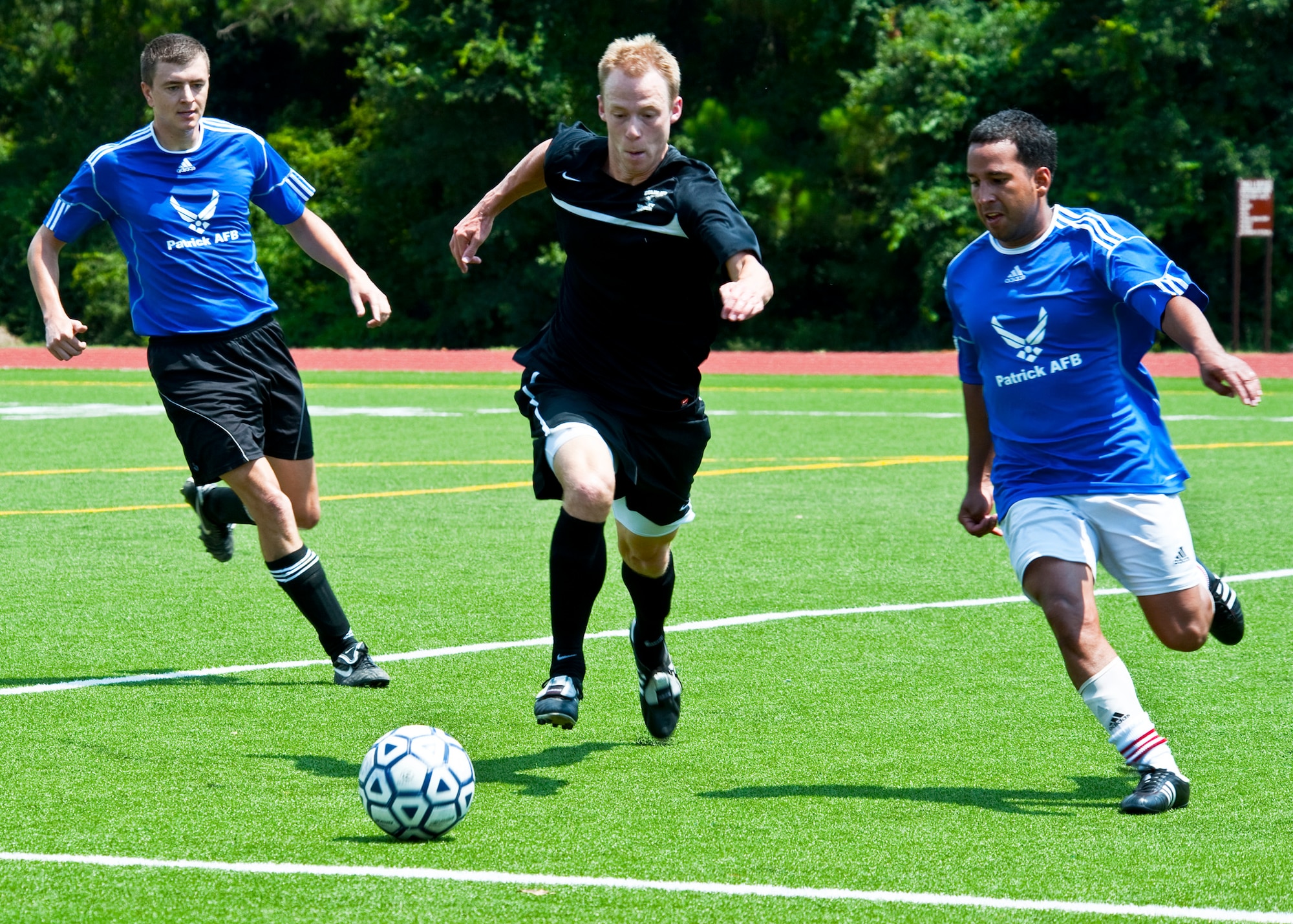 Kevin Birk (center) races two opponents for the ball at the military soccer tournament at Hurlburt Field July 9. Eglin's team defeated Patrick Air Force Base and Pensacola Naval Air Station. The games were a warm-up for the 2011 Defender’s Cup in San Antonio during Labor Day weekend. Eglin is the defending champion of the tournament.  (U.S. Air Force photo/Sachel Seabrook) 
