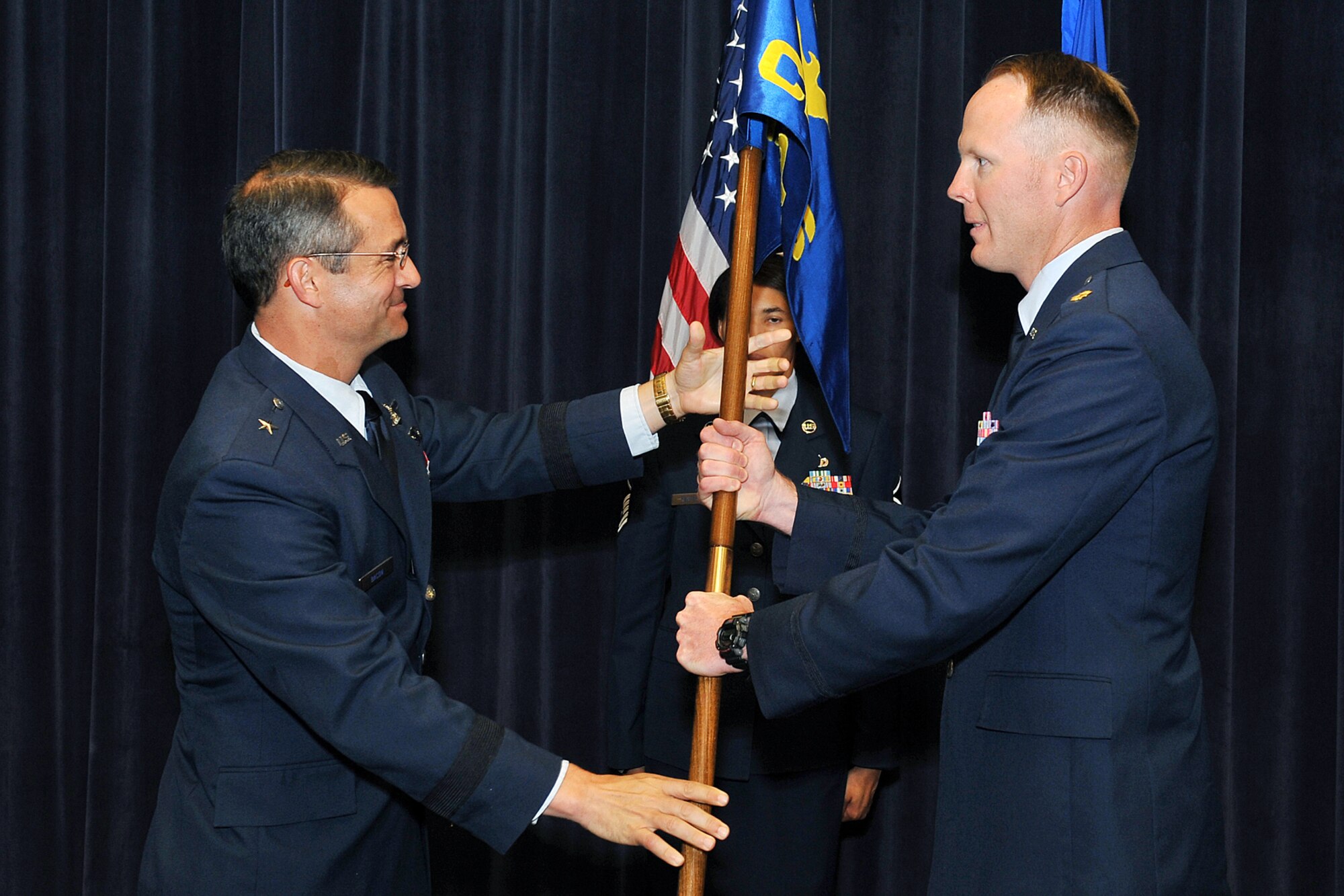 U.S. Air Force Brig. Gen. Donald Bacon, 55th Wing commander, passes the guidon to Maj. Darin Williams, incoming 55th Comptroller Squadron commander, during a change of command ceremony inside the Air Force Weather Agency's auditorium on Offutt Air Force Base, Neb., July 11. (U.S. Air Force Photo by Charles Haymond/Released)
