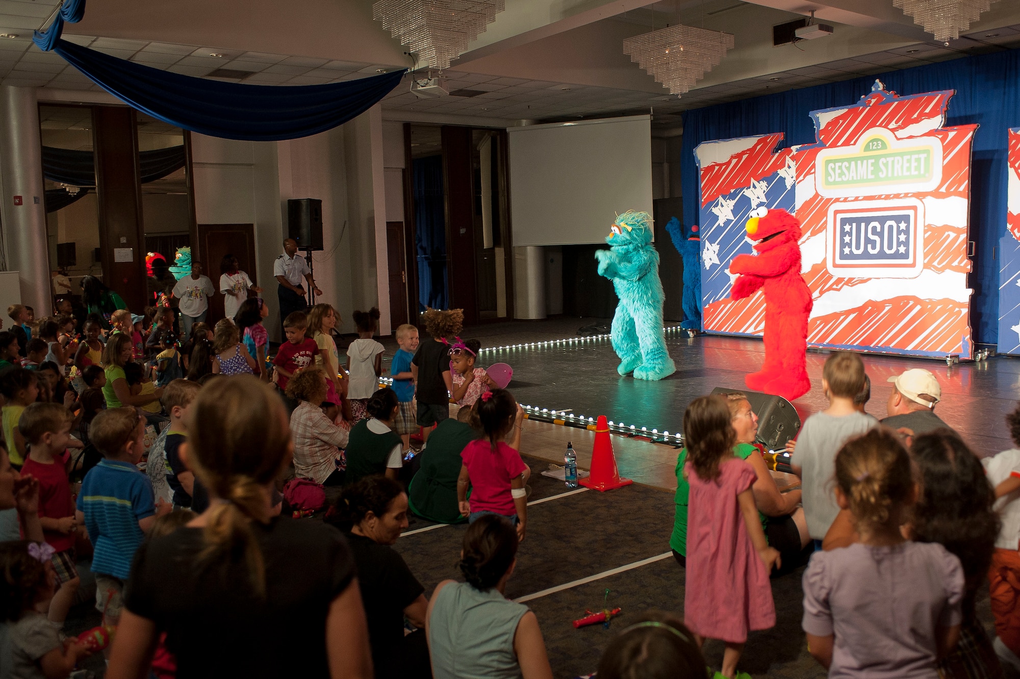 Sesame Street’s Elmo and Rosita perform the Elmo Slide for families of Team Incirlik during the Sesame Street/USO Experience July 11, 2011, at the Club Complex Ballroom at Incirlik Air Base, Turkey. The performance was part of a tour to U.S. military bases worldwide geared specifically toward helping children of military members deal with the stresses of deployment. (U.S. Air Force photo by Airman 1st Class Clayton Lenhardt/Released)