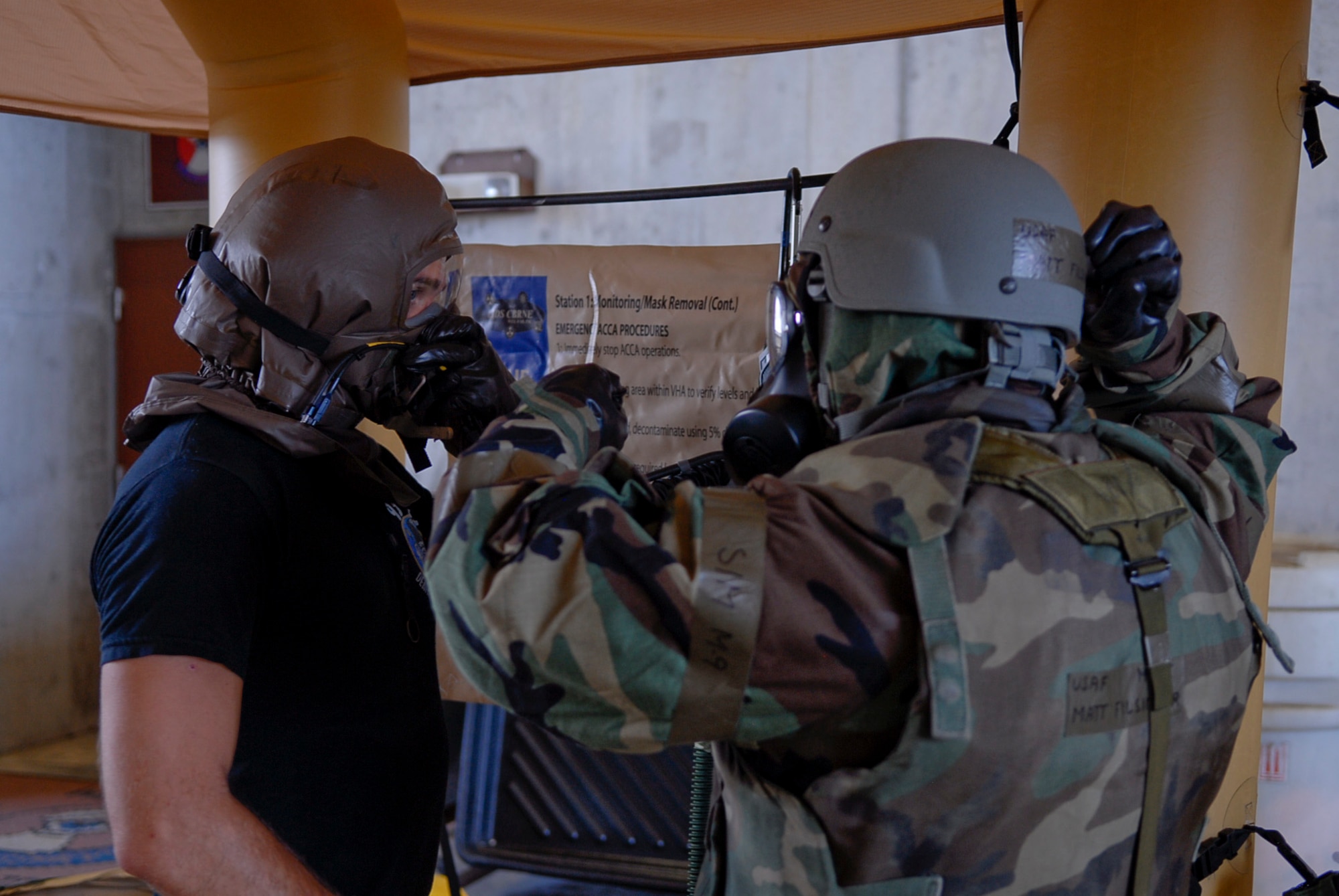 A Kadena aircrew member listens to a ground crew member giving a demonstration of mask removal as one of the last steps of a mock decontamination line July 12 during Beverly High 11-5, a Local Operational Readiness Exercise at Kadena Air Base, Japan. The LOREs performed on Kadena prepare the Airmen for real-world contingencies they may one day face. (U.S. Air Force photo/ Airman 1st Class Tara A. Williamson)