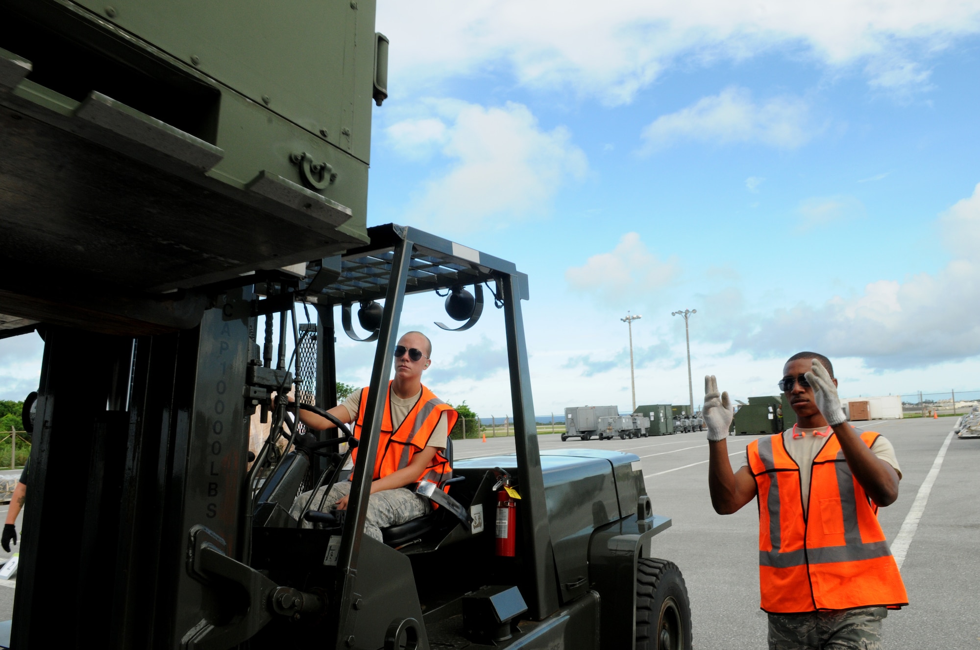 Airman 1st Class Tony Mathis, 18th Logistics Readiness Squadron vehicle mechanic, directs Airman Tammy Walbolt, 18th LRS vehicle mechanic, as she moves cargo July 12 during Beverly High 11-5, a Local Operational Readiness Exercise at Kadena Air Base, Japan. The LORE is an exercise that almost all Airmen at Kadena participate in to hone skills and keep them sharp in case of real-world emergencies. (U.S. Air Force photo/Airman 1st Class Jarvie Z. Wallace)
