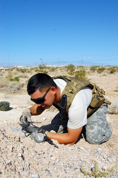 NELLIS AIR FORCE BASE, Nev. -- Senior Airman Andrew Ueno, 926th Civil Engineer Flight explosive ordnance disposal team member, measures an item found in the desert as part of a conventional weapons exercise here July 9. (U.S. Air Force photo/Capt. Jessica Martin)