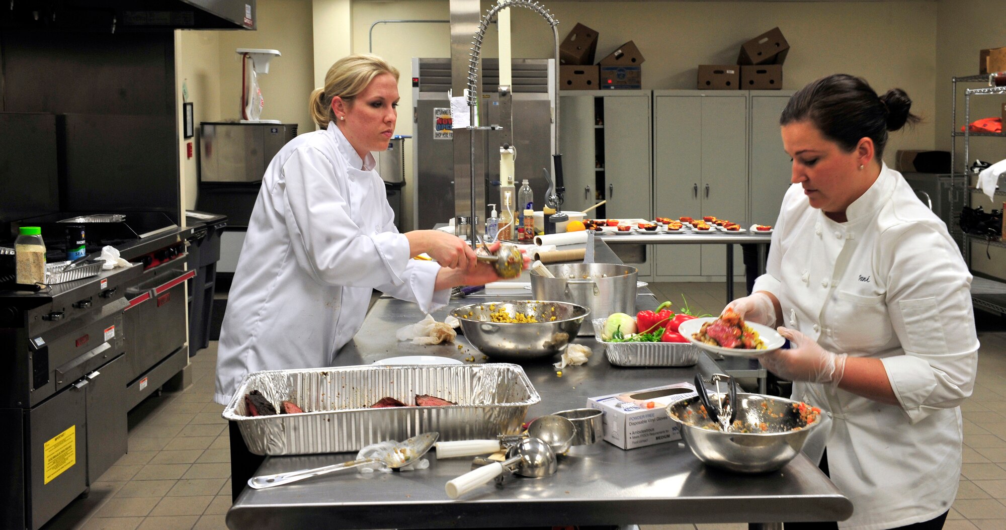 Staff Sgt. Amy Gillilan and Tech. Sgt. Danielle Sloan, flight attendants, artistically place food on plates to be served to 20 people on Scott Air Force Base, Ill June 29, 2011. Sergeant Gillilan and Sloan will be representing Scott at the 2011 Rodeo in the culinary competition.  In preparation for the event they have been cooking meals with the secret ingredient “beef” for multiple audiences to get feedback and improve the meal. (U.S. Air Force photo/Staff Sgt. Stephenie Wade)