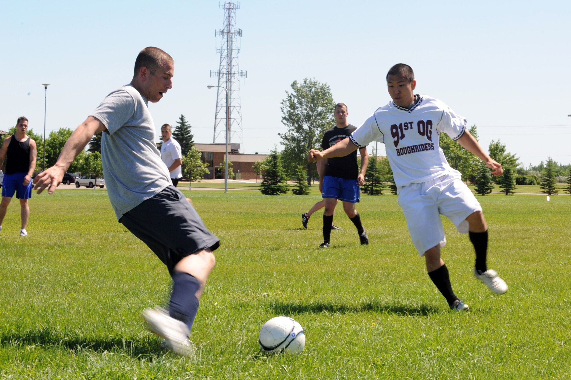 MINOT AIR FORCE BASE, N.D. -- Staff Sgt. Jeffrey Marino, 5th Maintenance Squadron aircraft electronics & environmental systems craftsman, clears a soccer ball after confronted by opponent 1st Lt. Casey Kawaguchi, 91st Operations Group missile crew combat commander, during a match here July 9. The McAdoo Sports and Fitness Center coordinates intramural soccer matches each year as a way of increasing unit cohesiveness and boosting base morale for all soccer aficionados. (U.S. Air Force photo/Airman 1st Class Jose L. Hernandez)