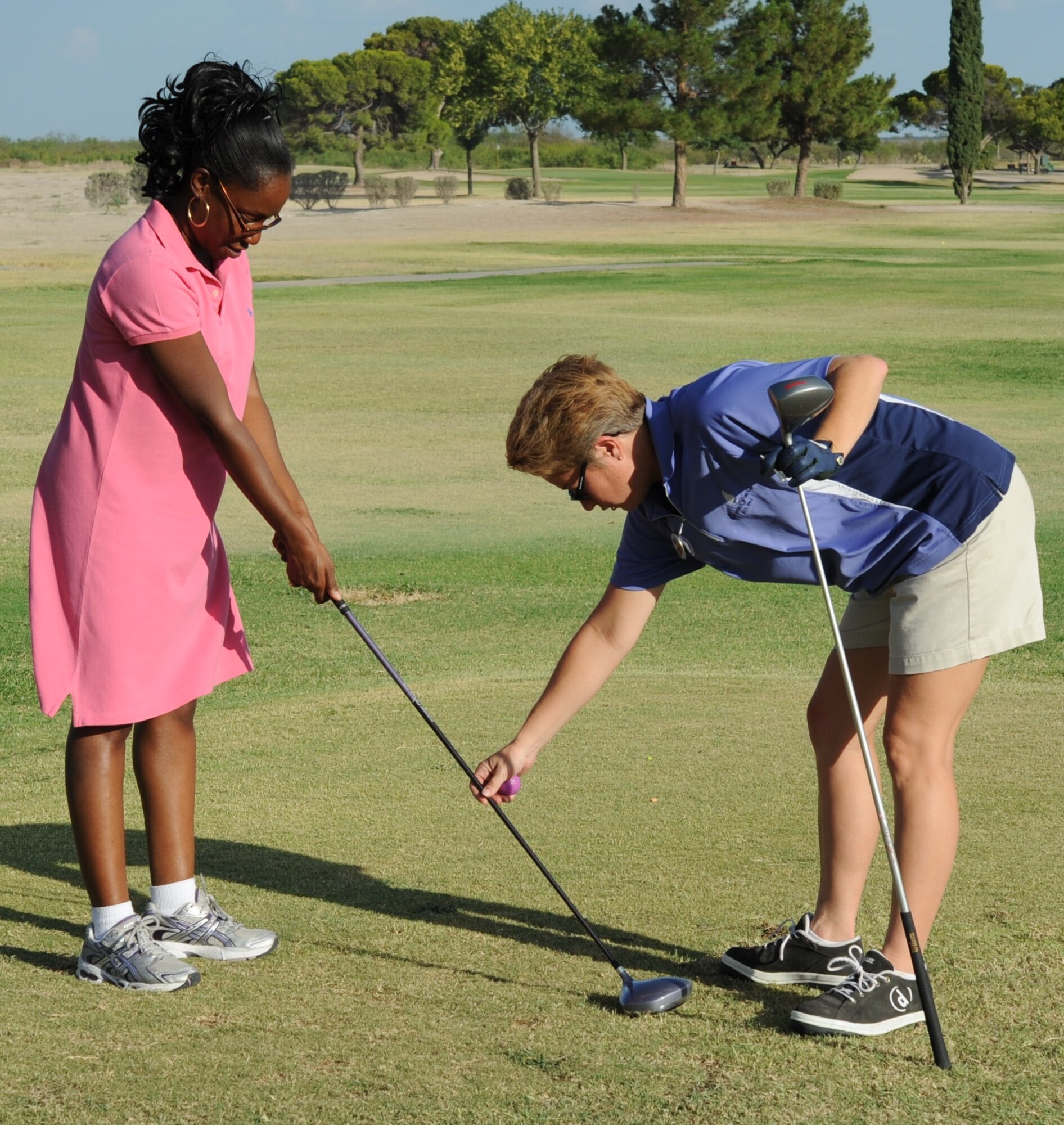 LAUGHLIN AIR FORCE BASE, Texas - - Kat Rawald, 47th Force Support Squadron recreation assistant, instructs Veronica McCoy, 47th FSS secretary, on the basics of teeing off at Laughlin’s Leaning Pine Golf Course during Wine and Tees. Wine and Tees is being offered at Leaning Pine Tuesday nights at 6:30 p.m., an exclusive event for women interested in playing golf. (U.S. Air Force photo by 2nd Lt. Angela Martin) 