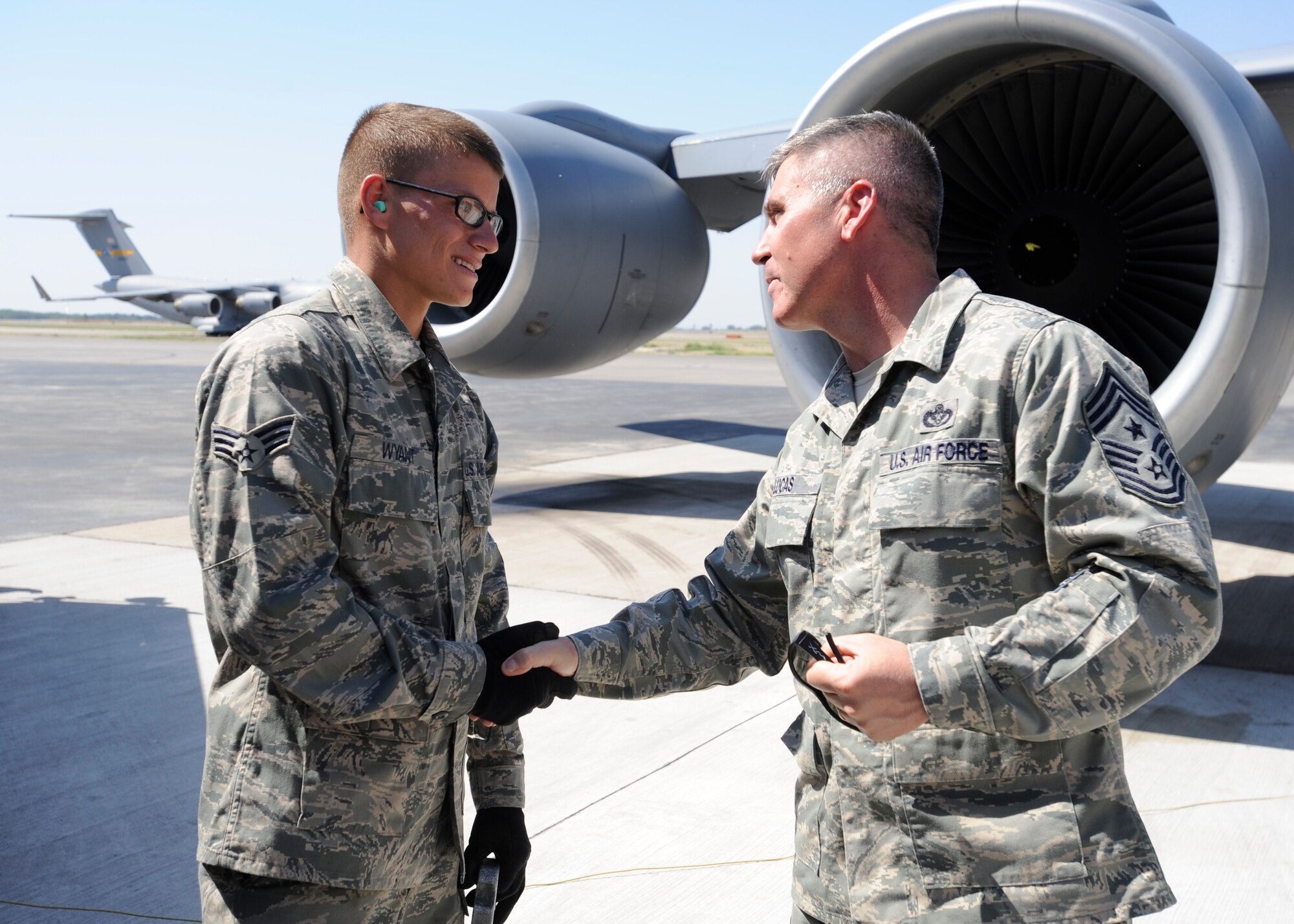Chief Master Sgt. James Lucas coins Senior Airman Chantz Wyant July 11 for pumping more than 5 million gallons of JP8 during his six-month deployment to the Transit Center at Manas, Kyrgyzstan. Wyant is a 376th Expeditionary Logistics Readiness Squadron fuels distribution operator deployed here from McConnell Air Force Base, Kan. He is a native of New Albany, Ohio. Lucas is the 376th Air Expeditionary Wing command chief. (U.S. Air Force photo/Tech. Sgt. Tammie Moore)