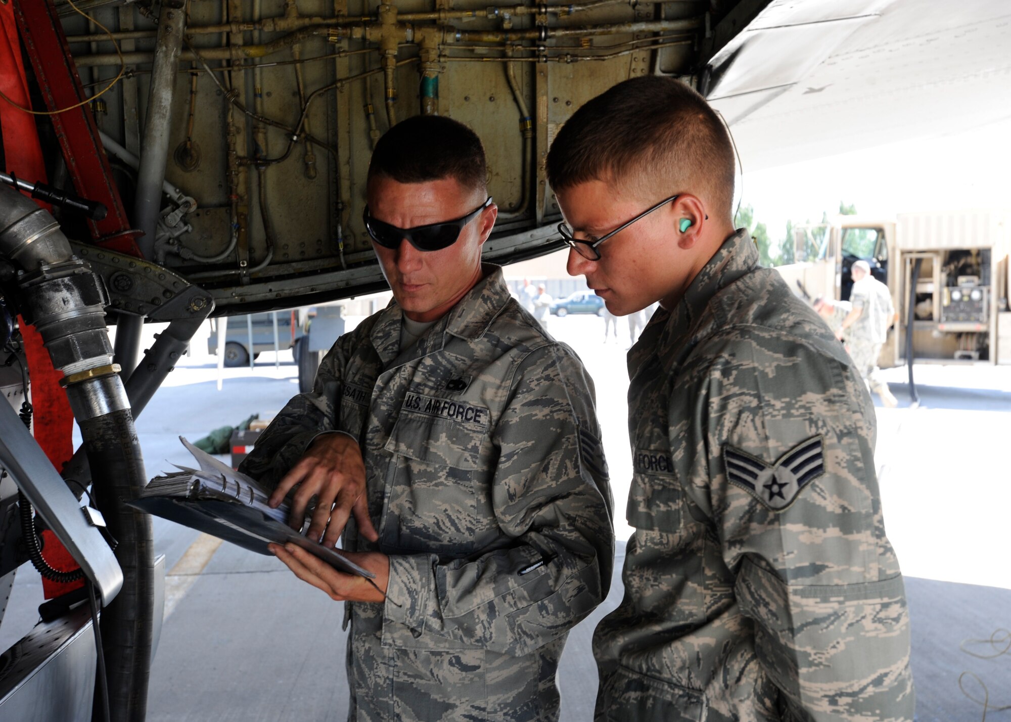 Senior Airman Chantz Wyant (r) receives a briefing from Staff Sgt. Kasey Hemesath before refueling a KC-135 Stratotanker at the Transit Center at Manas, Kyrgyzstan, July 11. While refueling this KC-135, Wyant achieved a deployment milestone by pumping more than 5 million gallons of JP8 during his time at the Transit Center. Wyant is a 376th Expeditionary Logistics Readiness Squadron fuels distribution operator deployed here from McConnell Air Force Base, Kan. Hemesath is deployed to the 376th Expeditionary Maintenance Group from Fairchild AFB, Wash. (U.S. Air Force photo/Tech. Sgt. Tammie Moore)