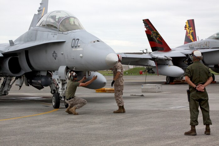 Brig. Gen. William D. Beydler, 1st Marine Aircraft Wing commanding general, waits in the cockpit of an F/A-18 Hornet while Marines of Marine All-Weather Fighter Attack Squadron 242 inspect the aircraft to ensure all components are in flying condition on the flightline here July 13. Beydler visited the air station to meet with Marines and sailors.